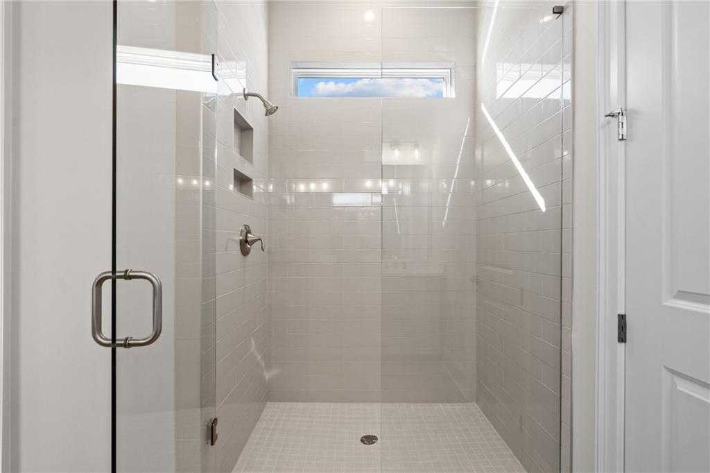 Modern frameless glass walk-in shower with subway tile, niche shelf, and transom window in The Arlington A master bath, East Cobb