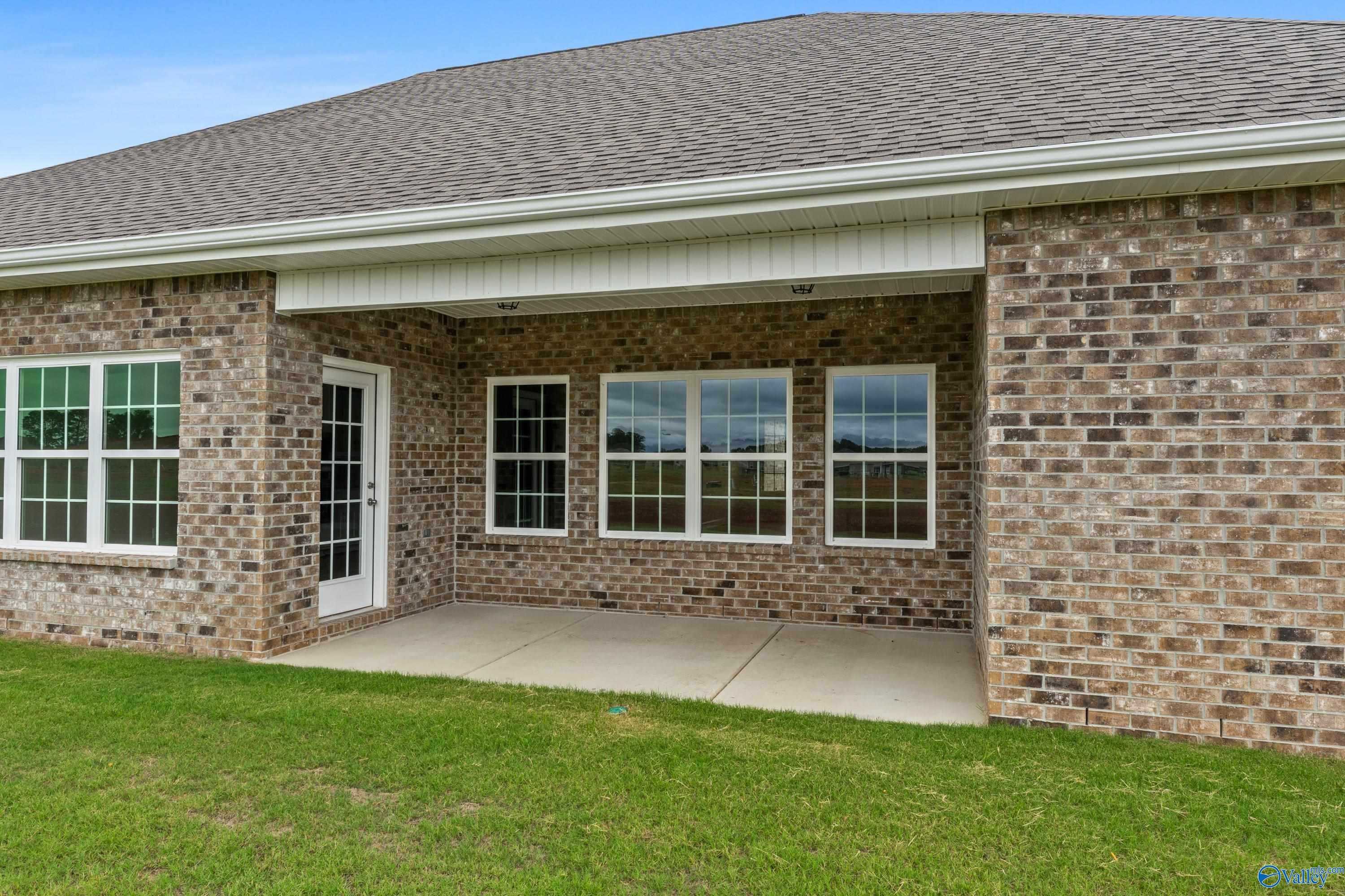 Covered back patio with brick exterior, large windows, and lush green lawn in Davidson Homes The Finleigh, Briercreek, Meridianville, Alabama