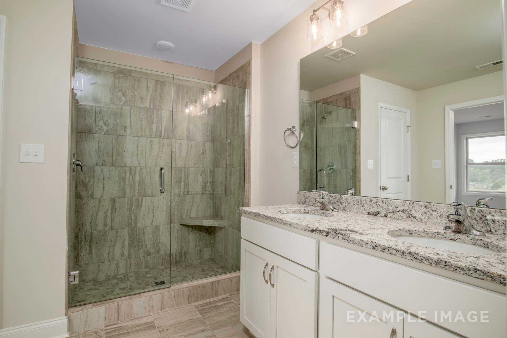 Master bathroom in The Charleston D featuring frameless glass shower with green subway tiles, double vanity, quartz countertop
