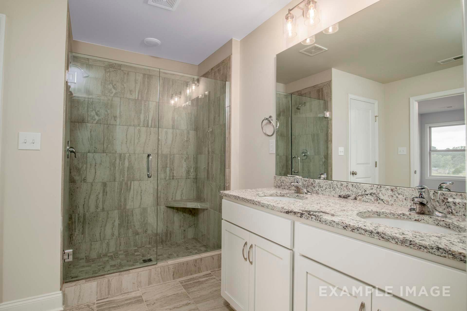 Master bathroom in The Charleston D featuring frameless glass shower with green subway tiles, double vanity, quartz countertop