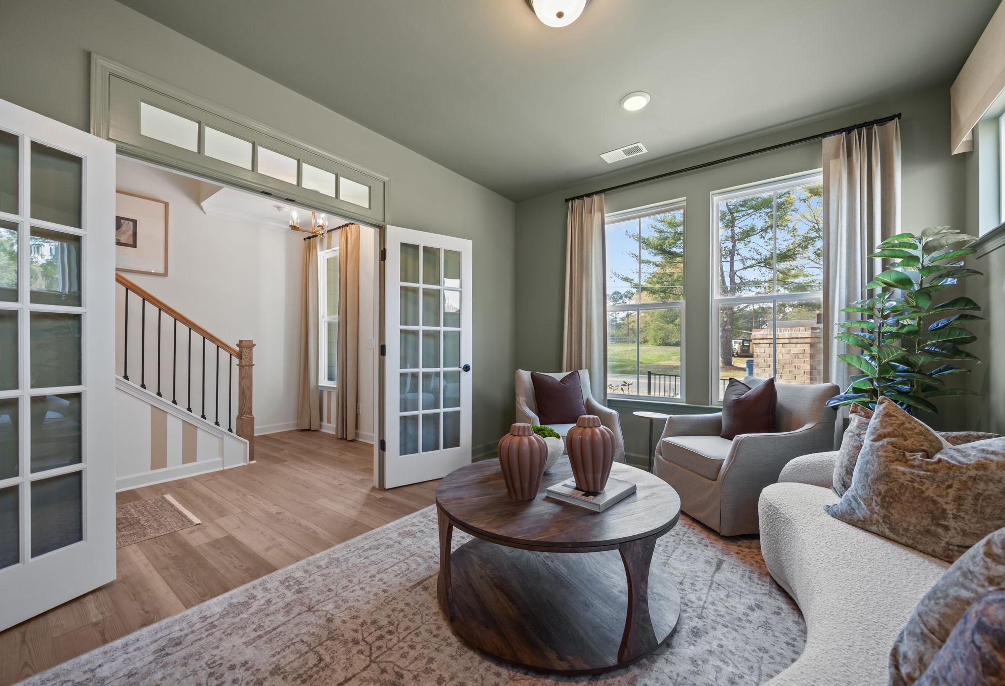Cozy sitting area in The Mitchell design featuring French doors, hardwood floors, and comfortable lounge seating.