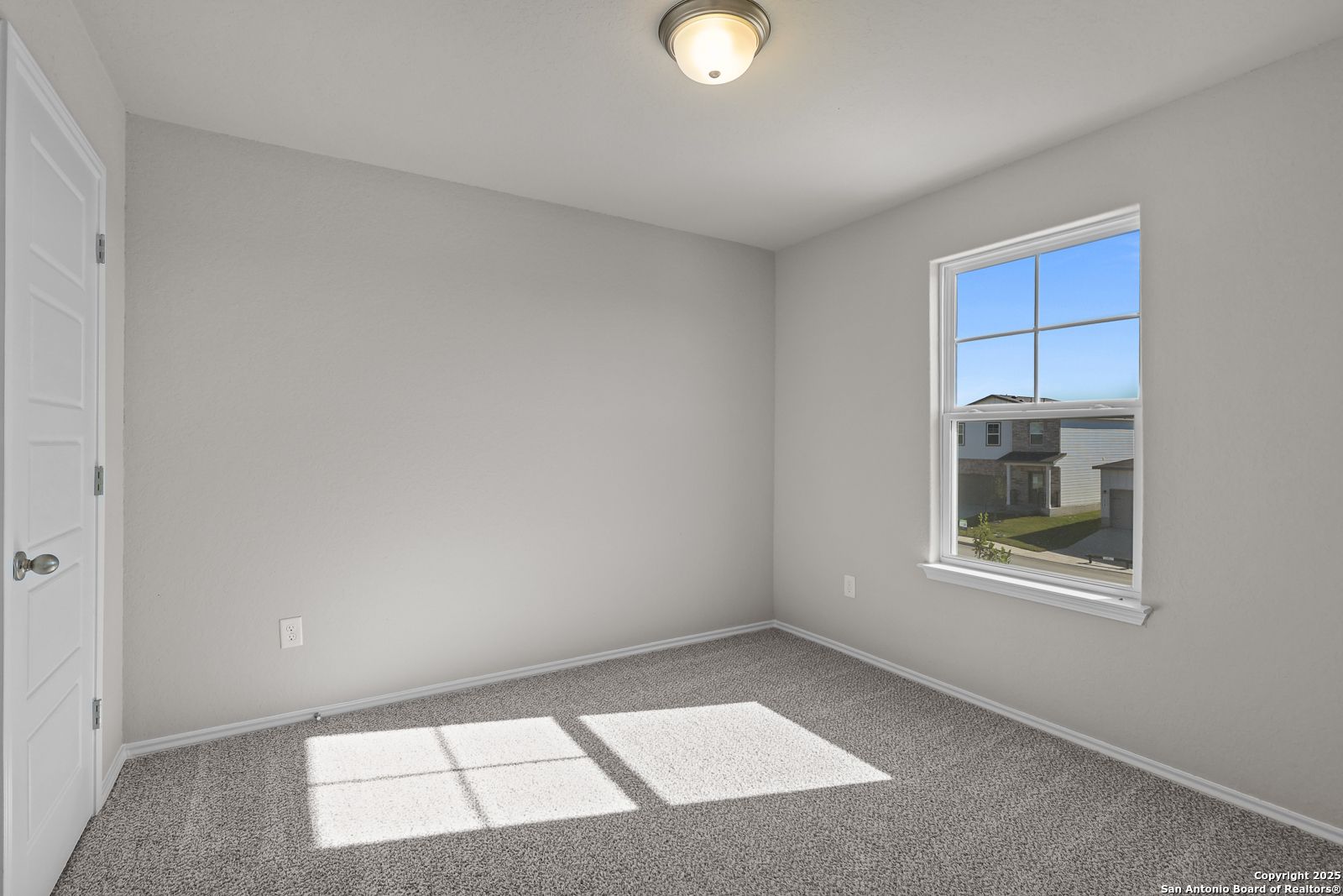 Bright secondary bedroom with gray walls, carpet floor, and window view of neighborhood in Davidson Homes The Trinity D, San Antonio