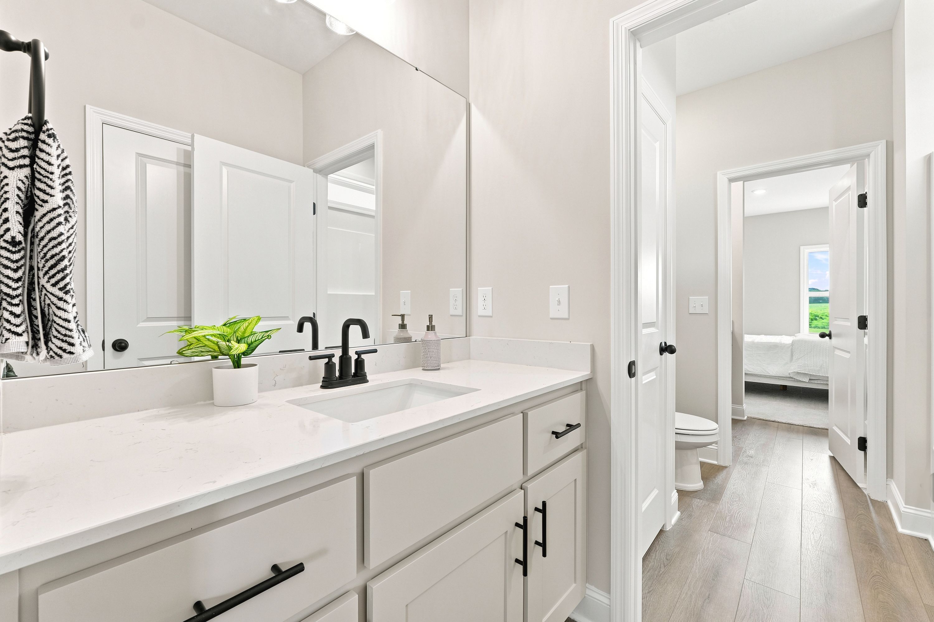 Modern bathroom at Riverton Preserve in Huntsville, AL with white quartz vanity, matte black fixtures, and wood-style floors.