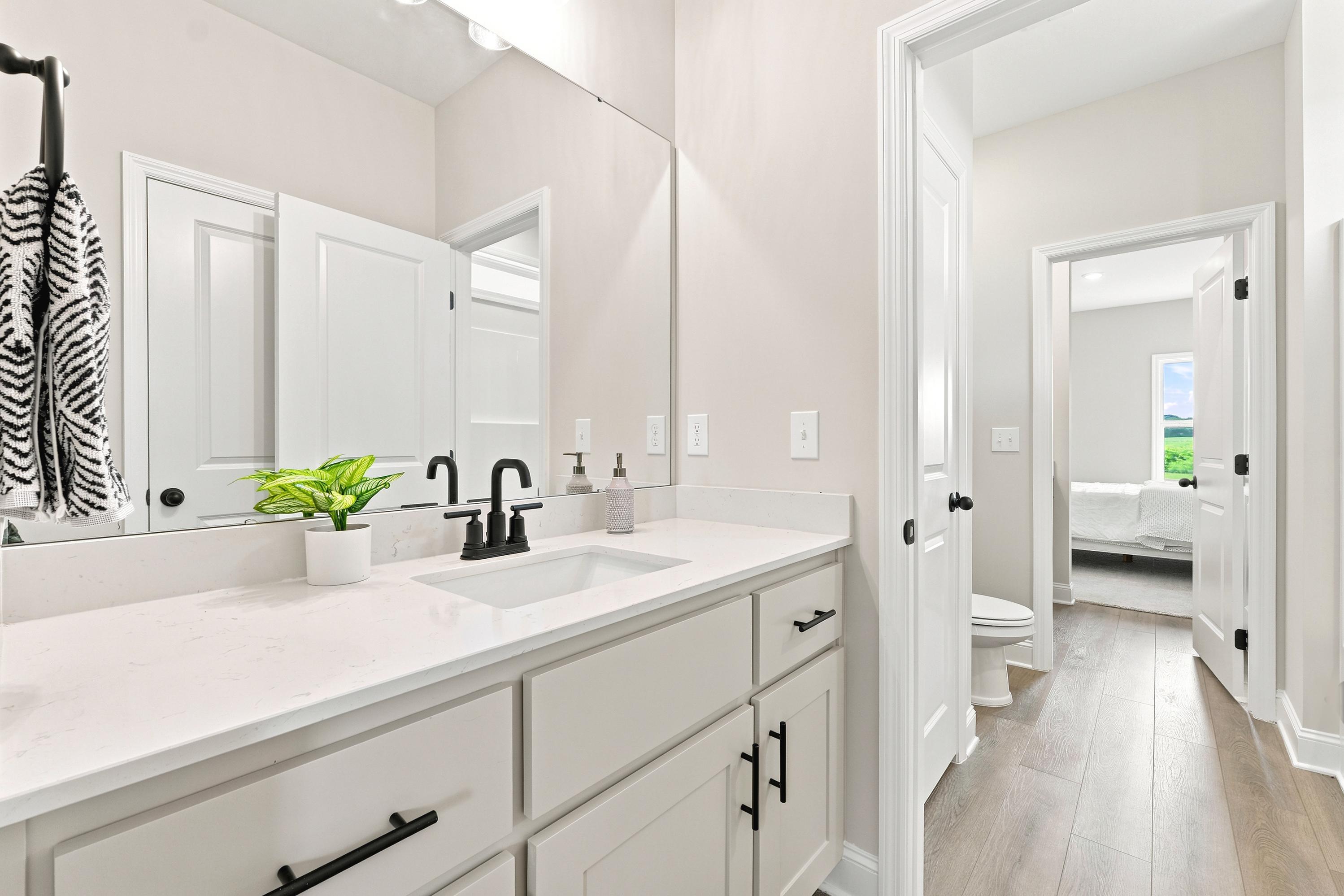 Modern bathroom at Riverton Preserve in Huntsville, AL with white quartz vanity, matte black fixtures, and wood-style floors.