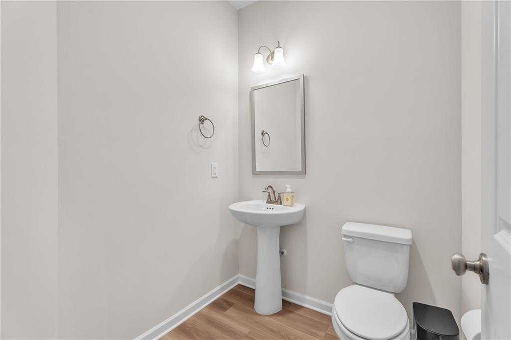 Elegant powder room with pedestal sink, toilet, framed mirror, and soft lighting in Davidson Homes The Bartlett, Phenix City, Alabama