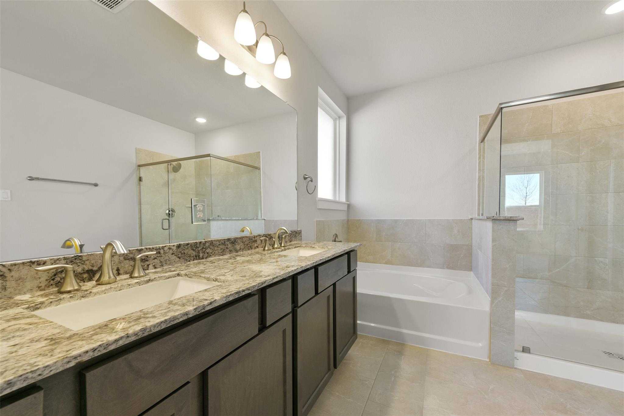 Elegant master bathroom featuring double granite vanity, soaking tub, and glass walk-in shower in Davidson Homes The Diana A, Lago Mar