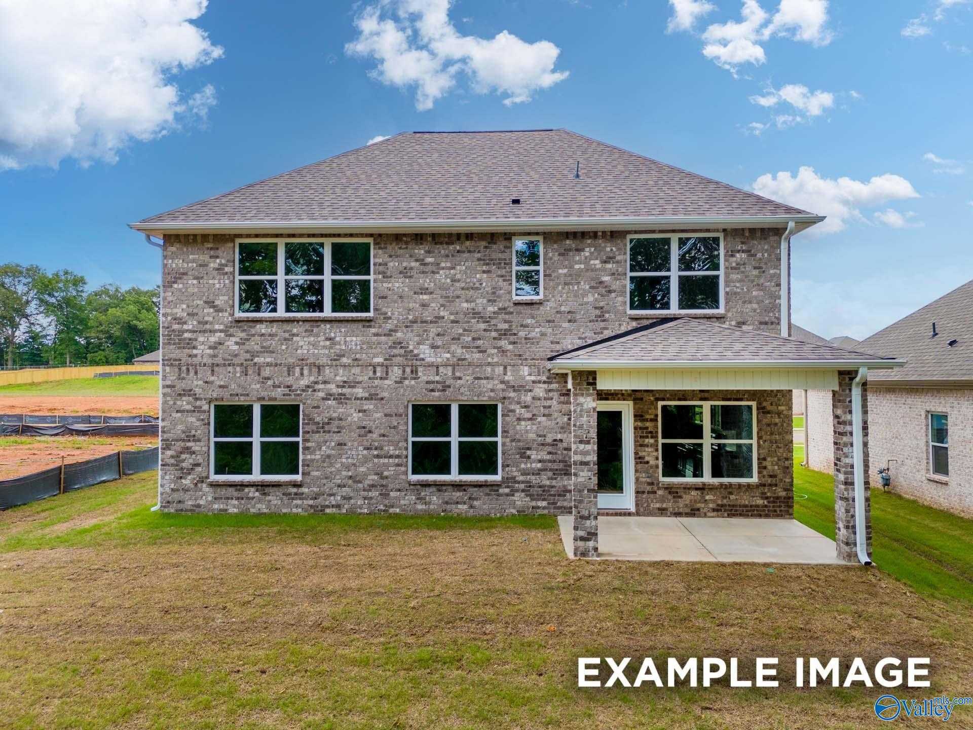 Rear view of two-story brick The Shelby C home with covered patio and green yard in Walker's Hill, Meridianville, Alabama