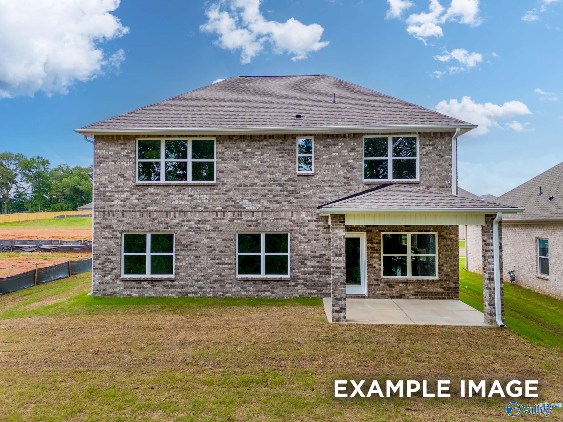 Rear view of two-story brick The Shelby C home with covered patio and green yard in Walker's Hill, Meridianville, Alabama