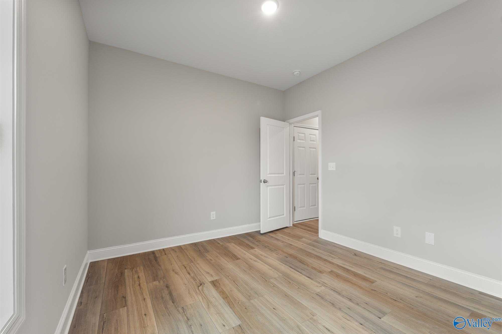 Spacious secondary bedroom with hardwood floors and neutral gray walls in Davidson Homes The Daphne D, Athens, AL