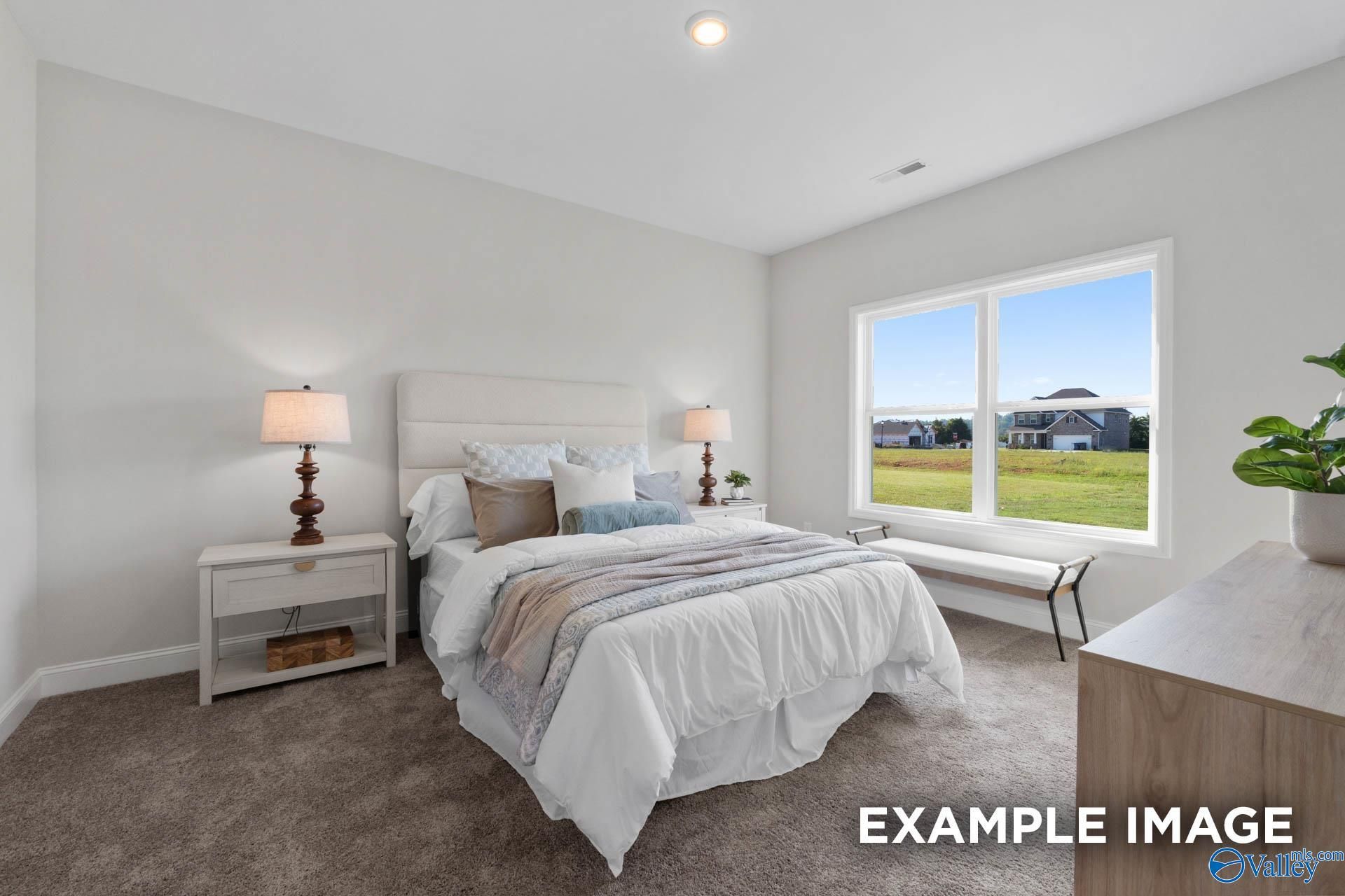 Bright bedroom with plush bedding and large window in The Franklin C floor plan at Heritage Lakes, New Market, Alabama.