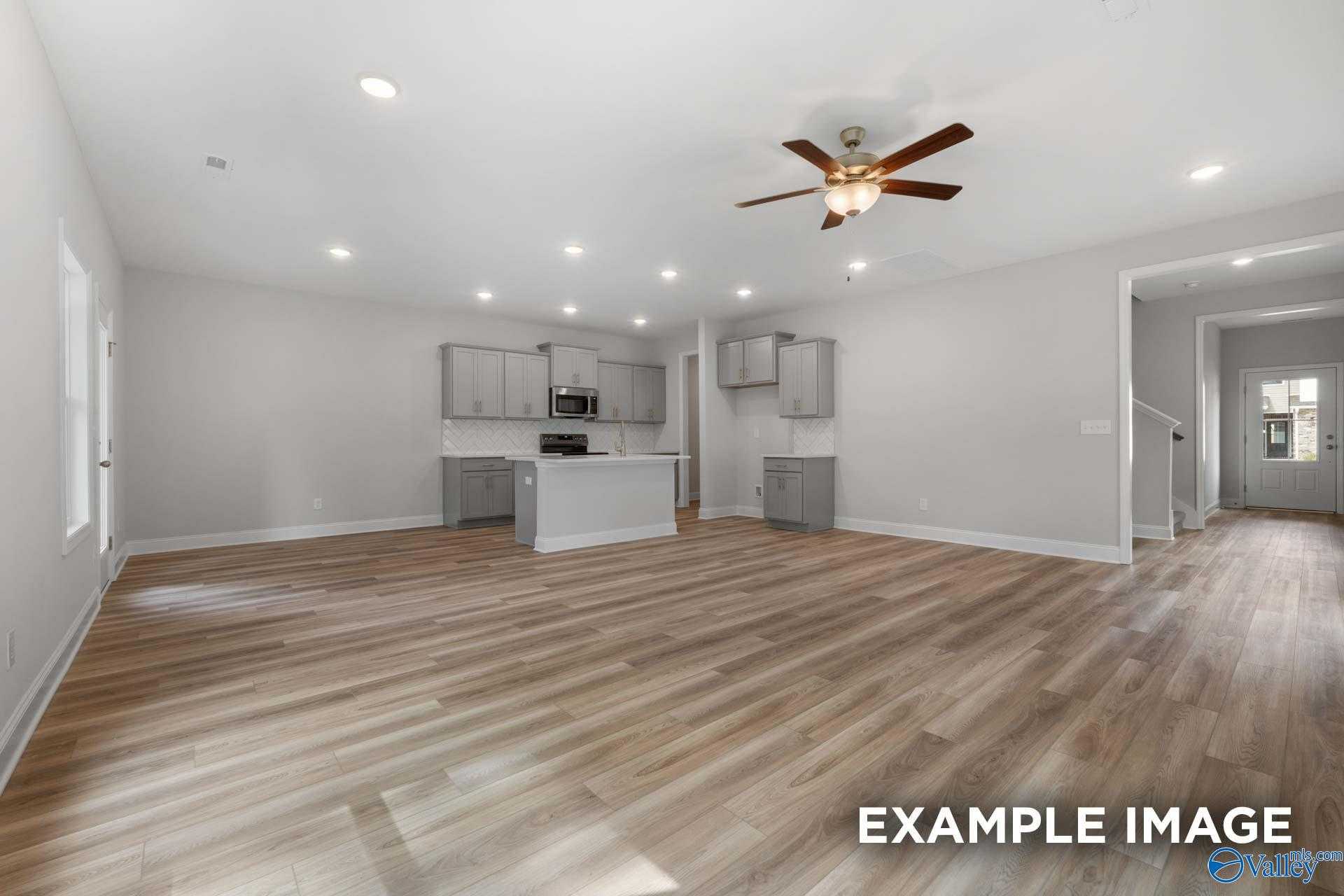 Modern open kitchen with gray shaker cabinets, white quartz island, hardwood floors, ceiling fan in The Camden by Davidson Homes, Huntsville AL