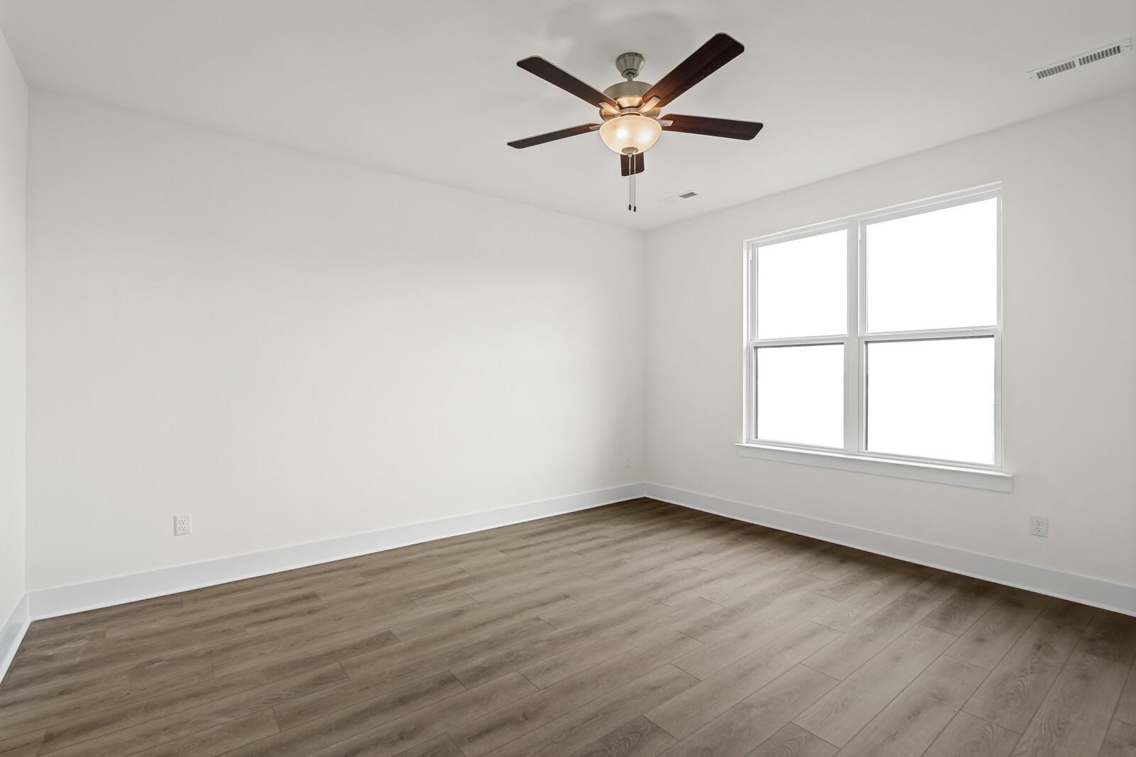 Bright bedroom with wood-look flooring and ceiling fan in The Ridgeport D floor plan, Benders Cove, Mt. Juliet, Tennessee.