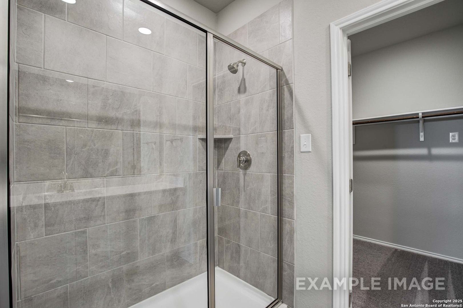Modern walk-in shower with frameless glass door, gray subway tiles, and niche in master bath of Davidson Homes The Blanco C, San Antonio