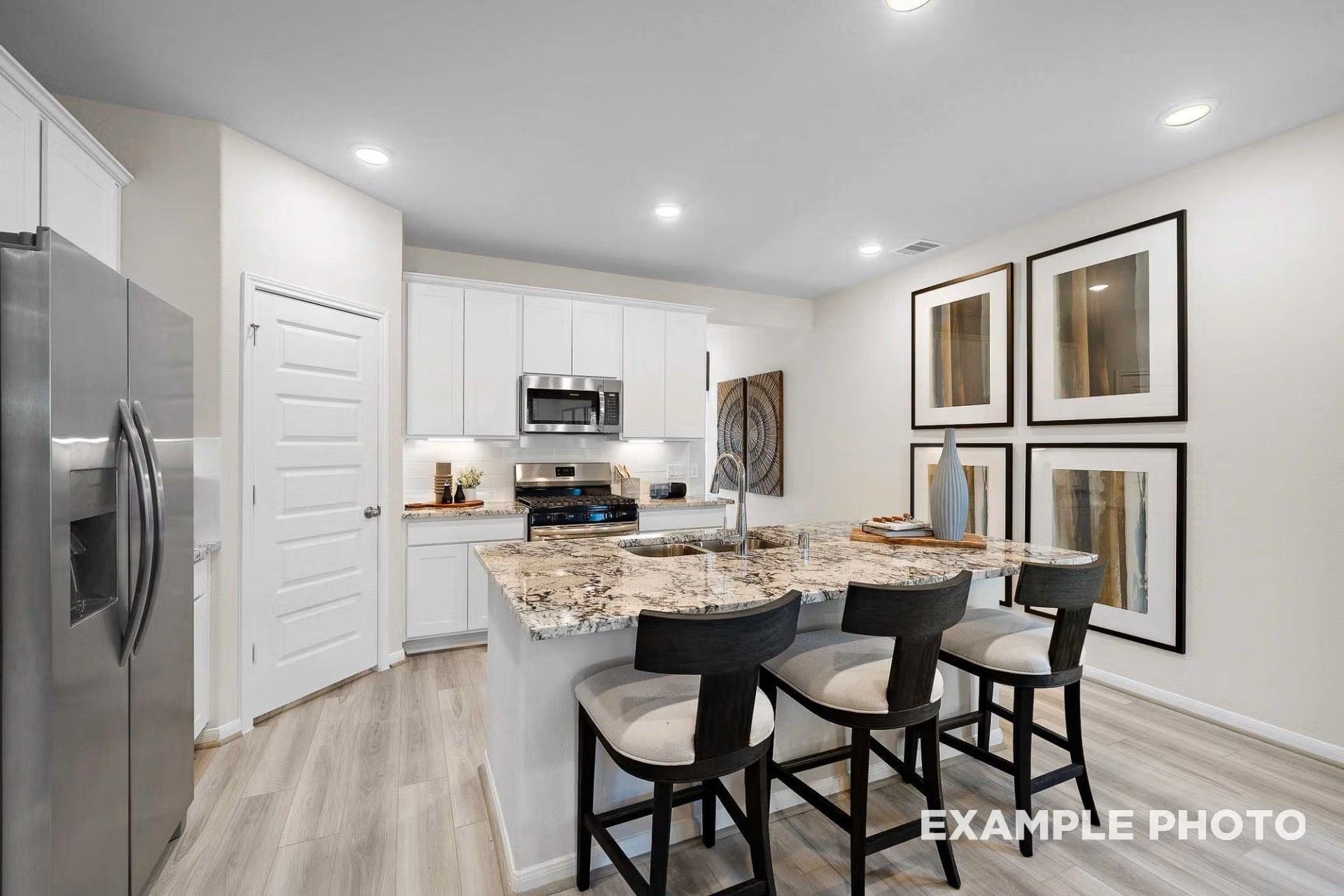 Modern kitchen with white cabinets, granite island, and bar seating in Davidson Homes The San Marcos E in Heartland, TX.