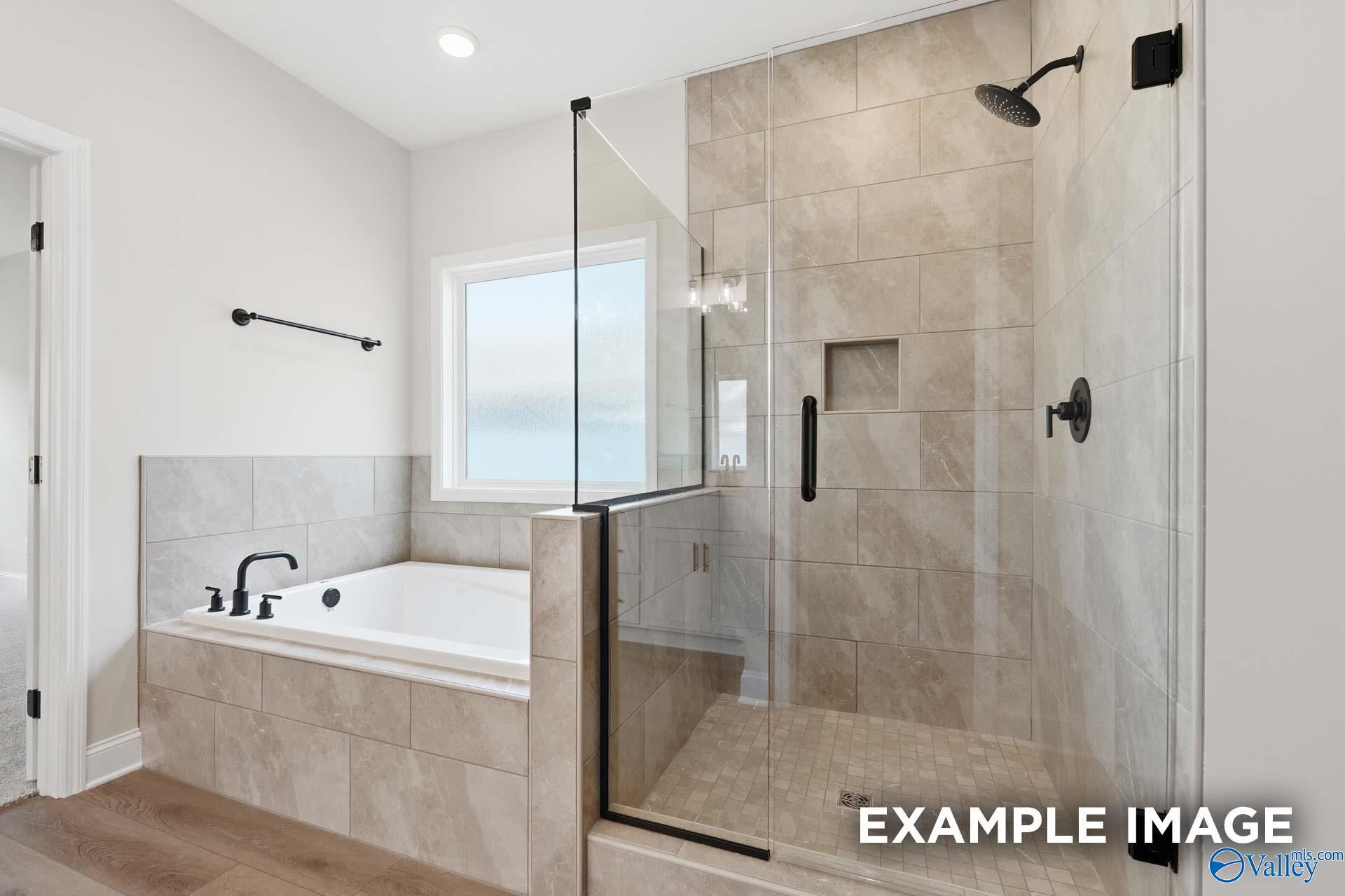 Modern primary bathroom with walk-in tile shower and soaking tub in The Rockford C floor plan at Evergreen Mill, Madison.