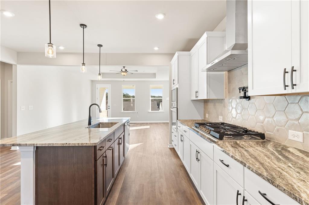 Modern kitchen with white shaker cabinets, large quartz island, gas range, and hex tile backsplash in Davidson Homes Glenwood A, Loganville, GA