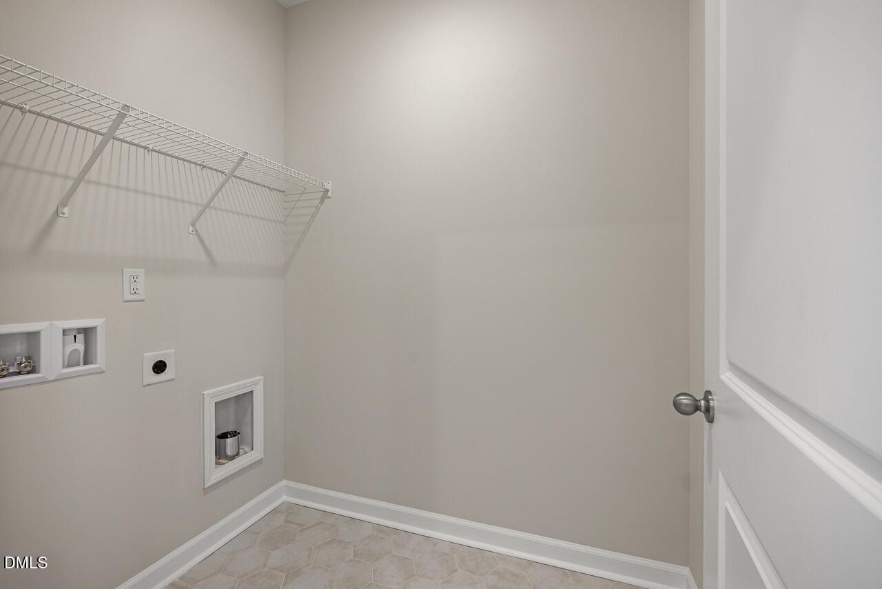 Laundry room with wire shelving and utility hookups in The Alexander C floor plan at Forestville Yard, Knightdale, NC.