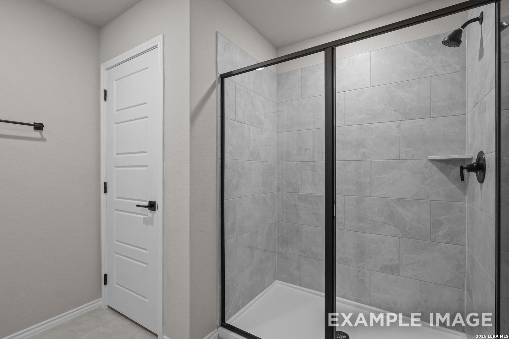 Modern walk-in shower with gray tile and matte black fixtures in The Murray H home by Davidson Homes, Converse, Texas