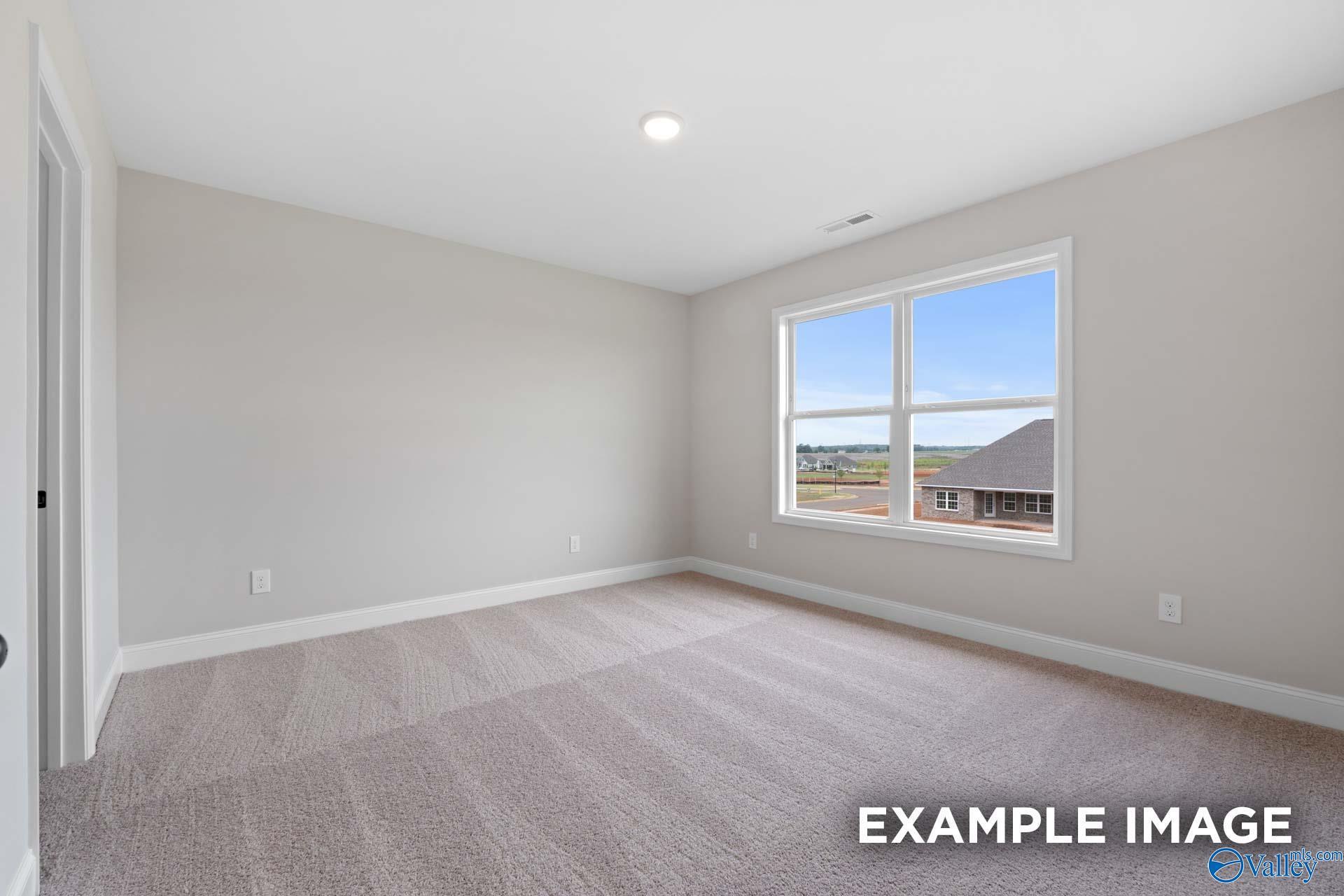 Bright, carpeted bedroom with neutral walls and large window in The Shelby B floor plan, Jaguar Hills, Huntsville, AL.