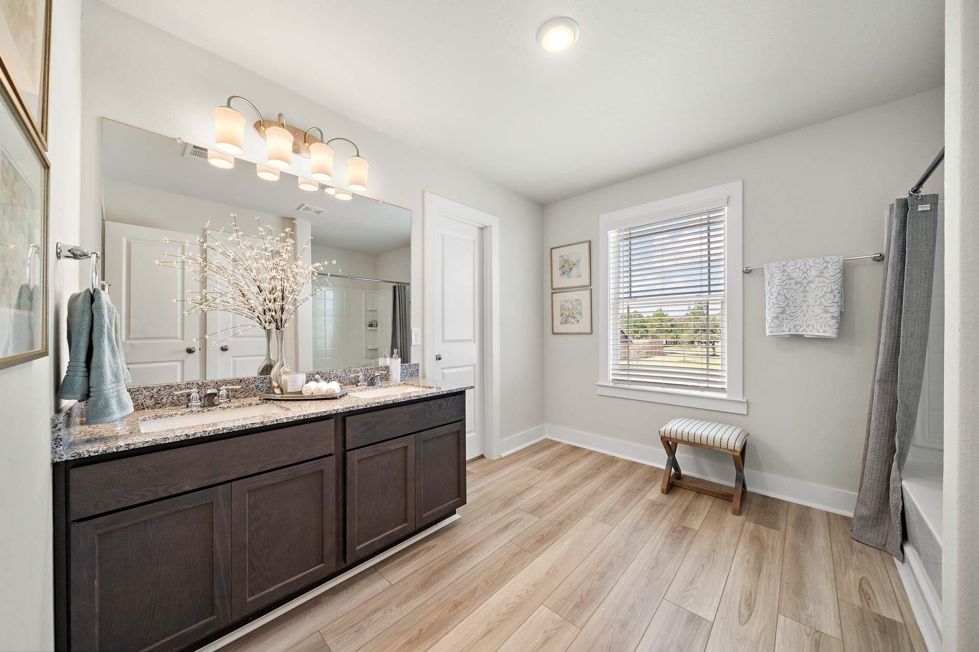 Spacious master bathroom at Haven at Kieth Harrow in Cypress Texas with double dark wood vanity, quartz counters, wood floors, and walk-in shower