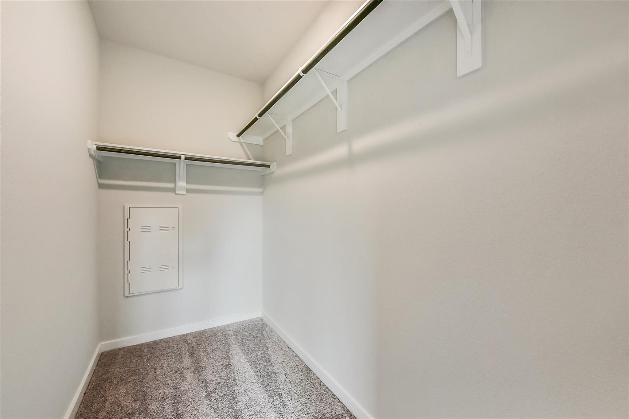 Spacious walk-in closet with double rods, neutral walls, carpet floor in Davidson Homes The Frio G, Dayton Texas