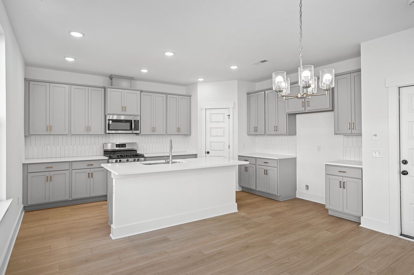Modern kitchen with gray shaker cabinets, white quartz island, stainless appliances in The Logan C by Davidson Homes, Gallatin, TN
