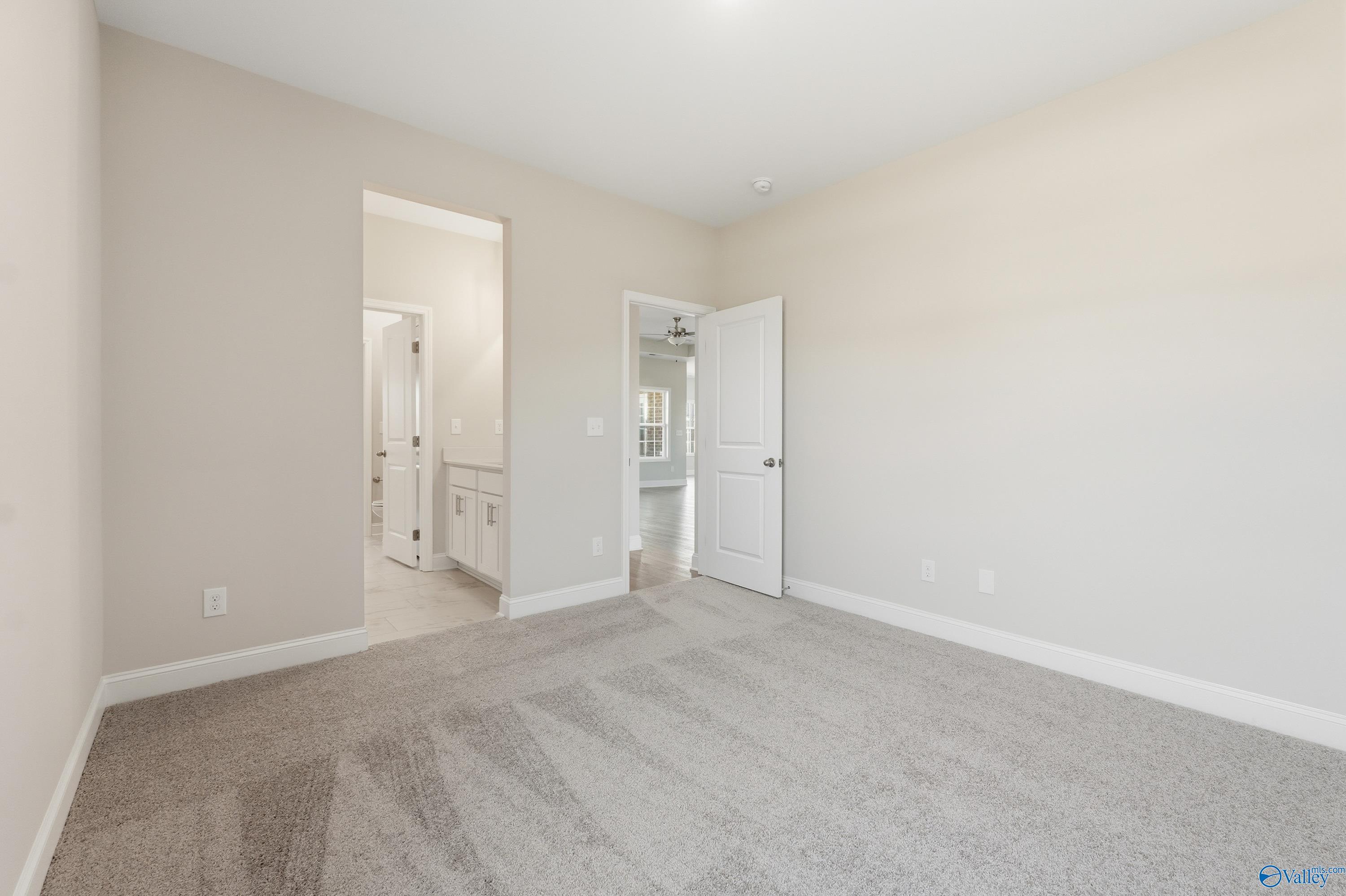Spacious master bedroom with en-suite bathroom featuring vanity and double doors in The Finleigh floor plan, Creekside, Harvest, Alabama