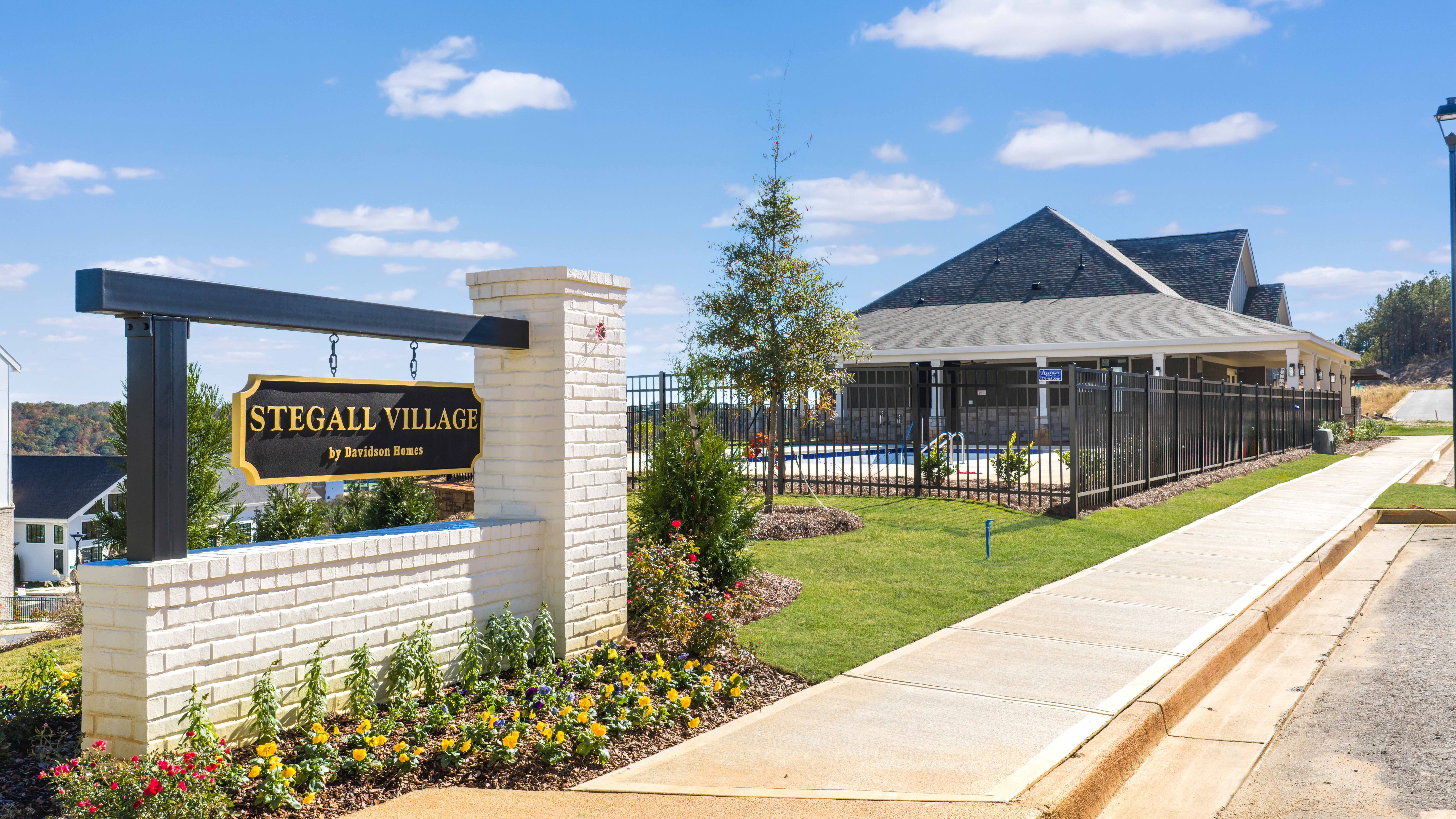 Stegall Village gated entrance in Emerson Georgia with welcome sign brick pillars evergreen trees and poolside landscaping