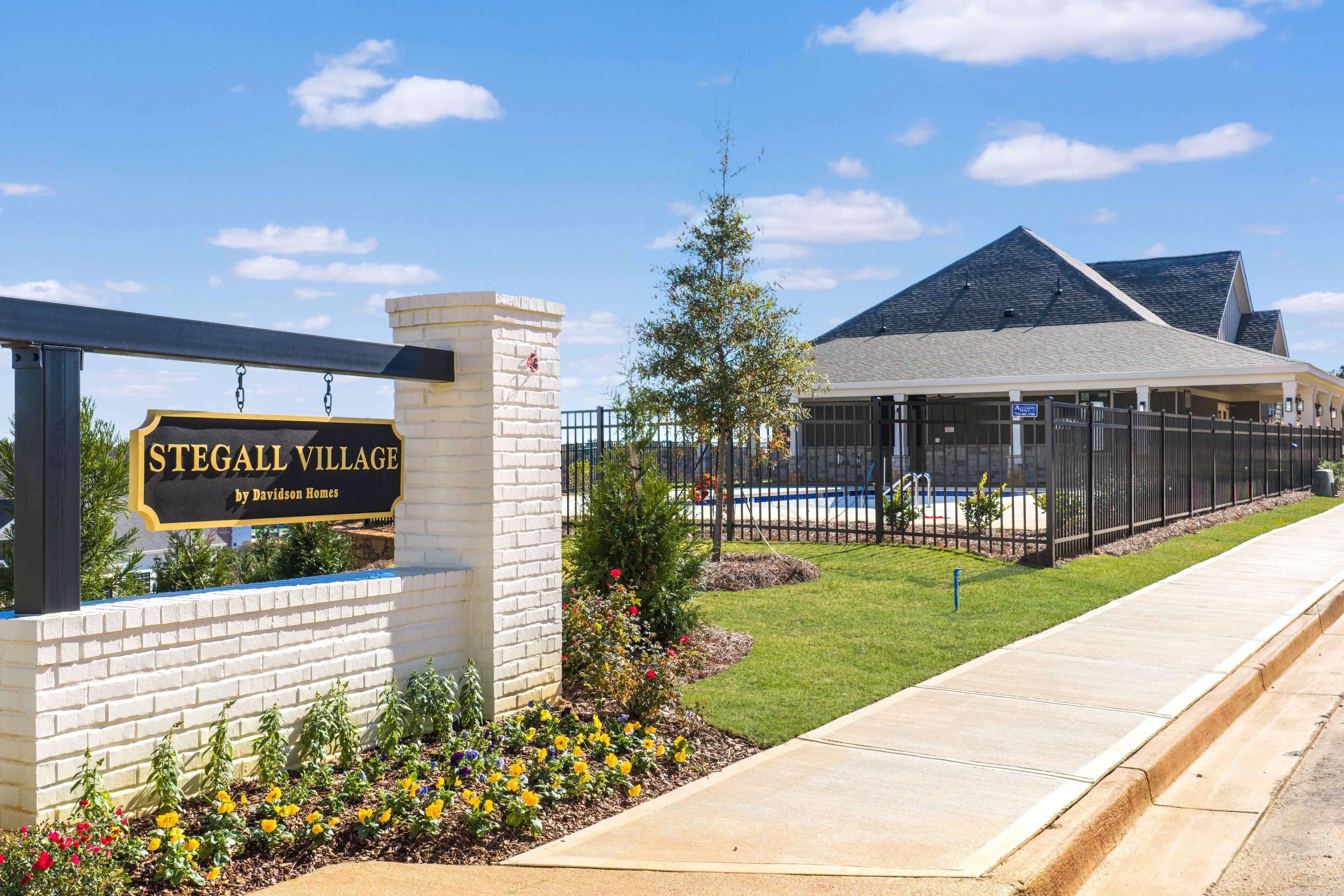 Stegall Village gated entrance in Emerson Georgia with welcome sign brick pillars evergreen trees and poolside landscaping