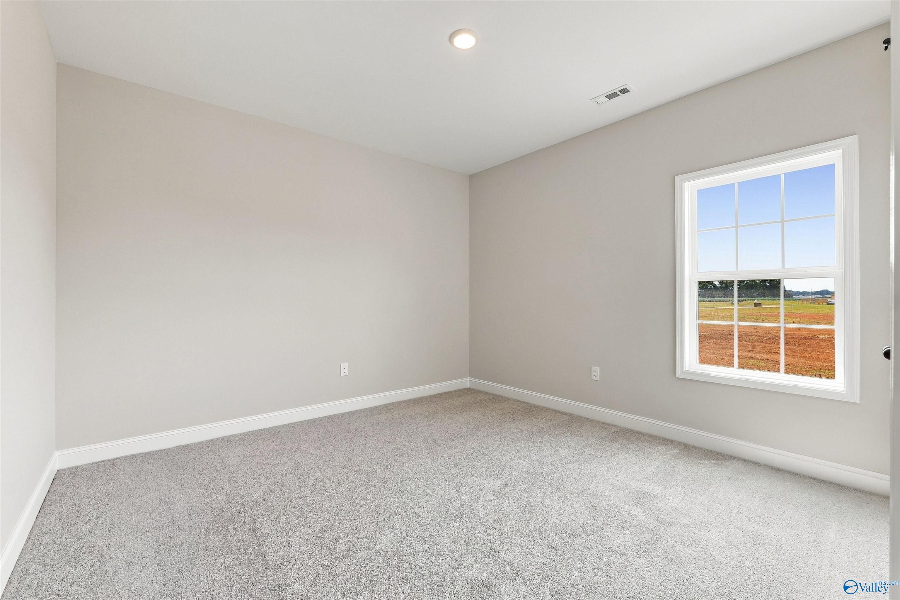 Spacious secondary bedroom with neutral carpet and natural light in The Oxford floor plan at Kendall Farms, Toney, Alabama.