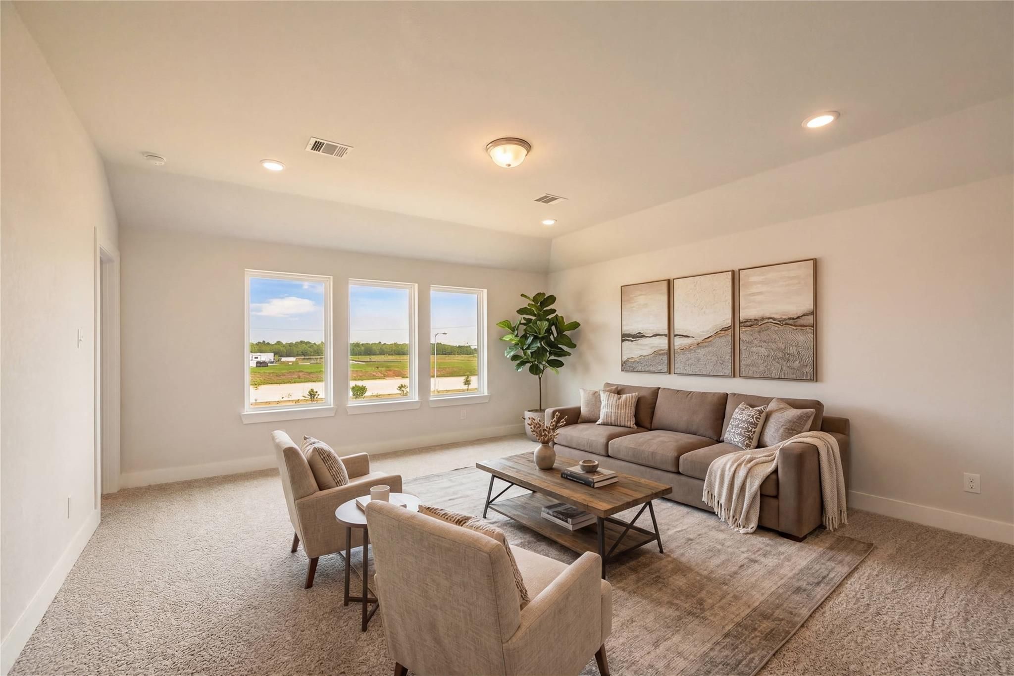 Bright living room with large windows overlooking Texas fields, neutral sofa, armchairs, and fiddle leaf fig in Davidson Homes The Philip A, Lago Mar