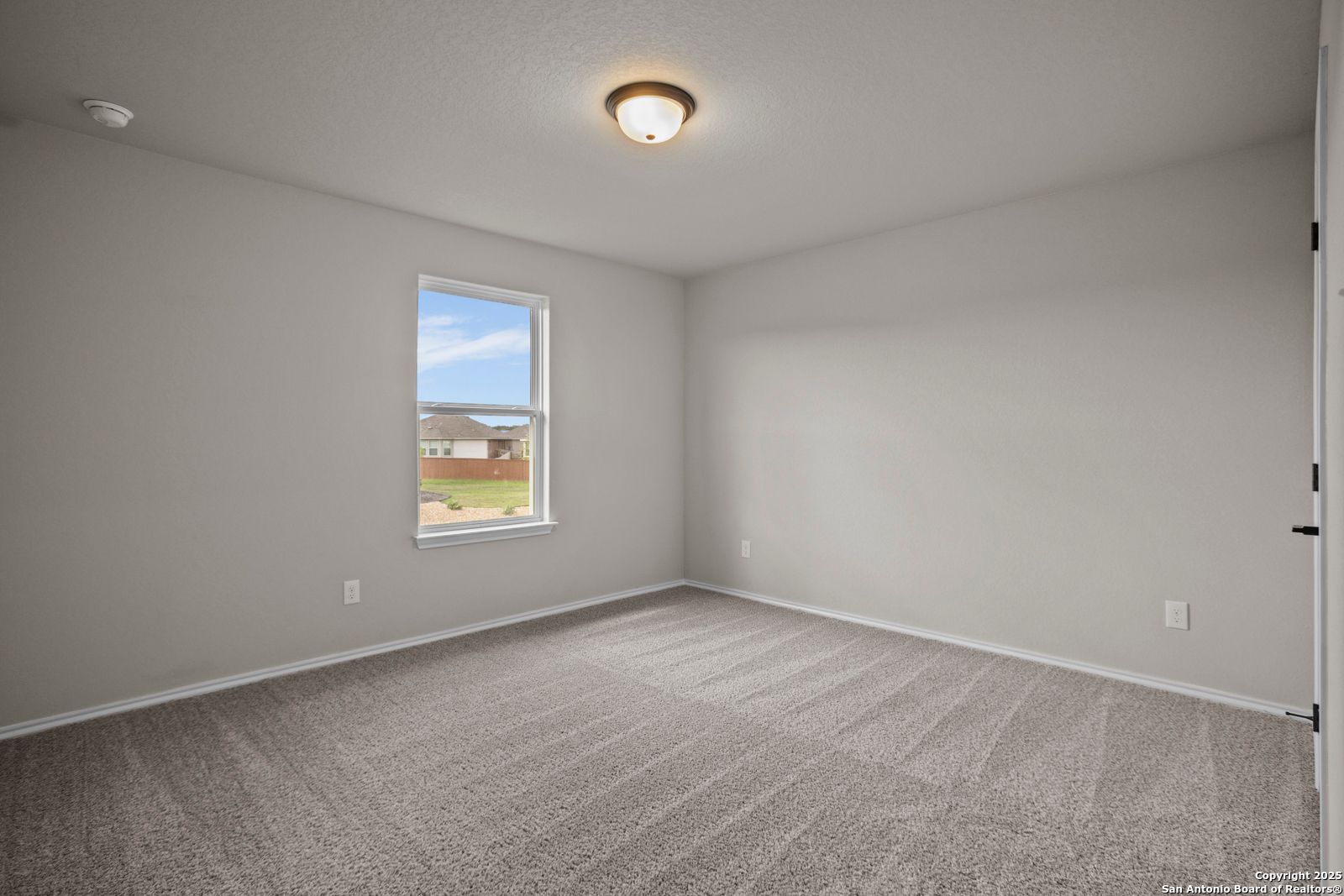 Empty secondary bedroom featuring light gray walls, plush carpet, and sunny window in Davidson Homes The Douglas F, Comanche Ridge, San Antonio