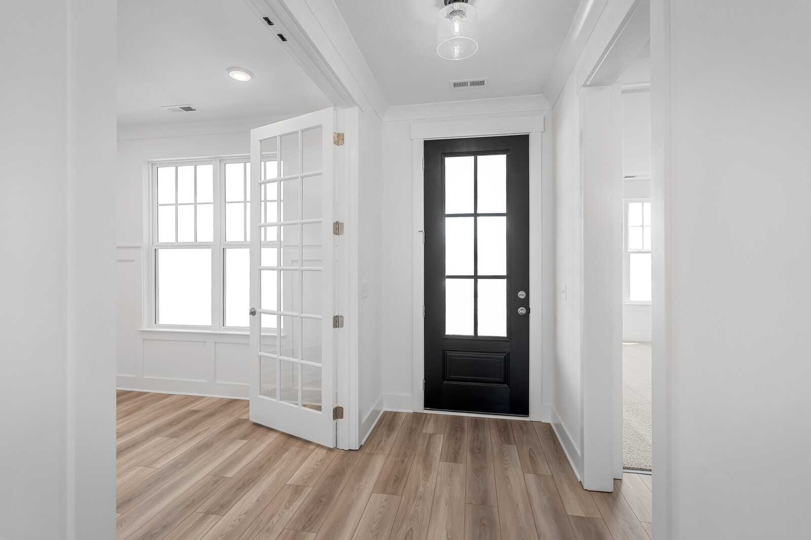 Modern foyer with black glass front door, white French doors, and hardwood floors in Davidson Homes The Hathaway, Murfreesboro, Tennessee