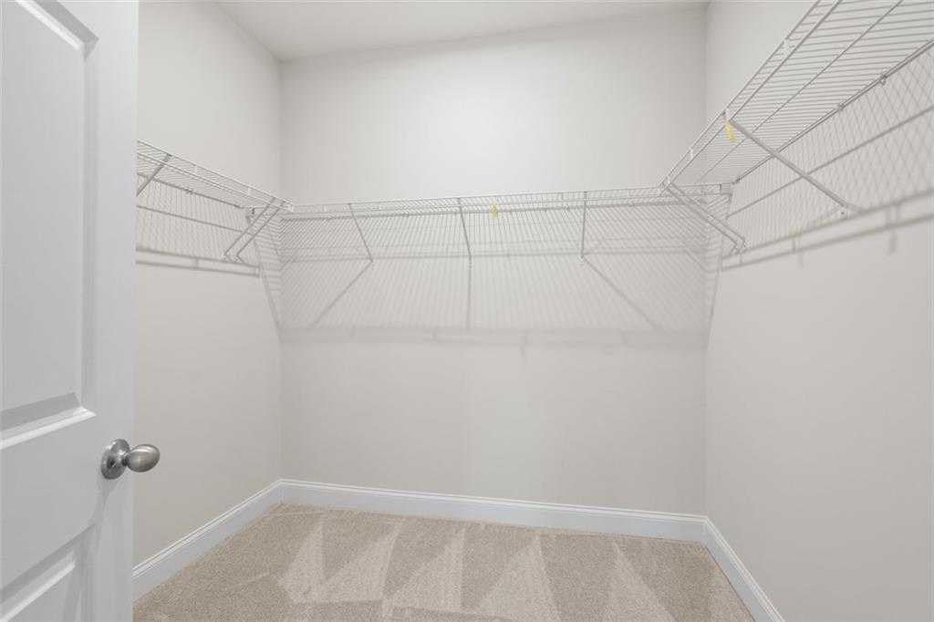 Spacious walk-in closet with wire shelving and open door in Davidson Homes The Ash C at Wehunt Meadows, Hoschton, Georgia
