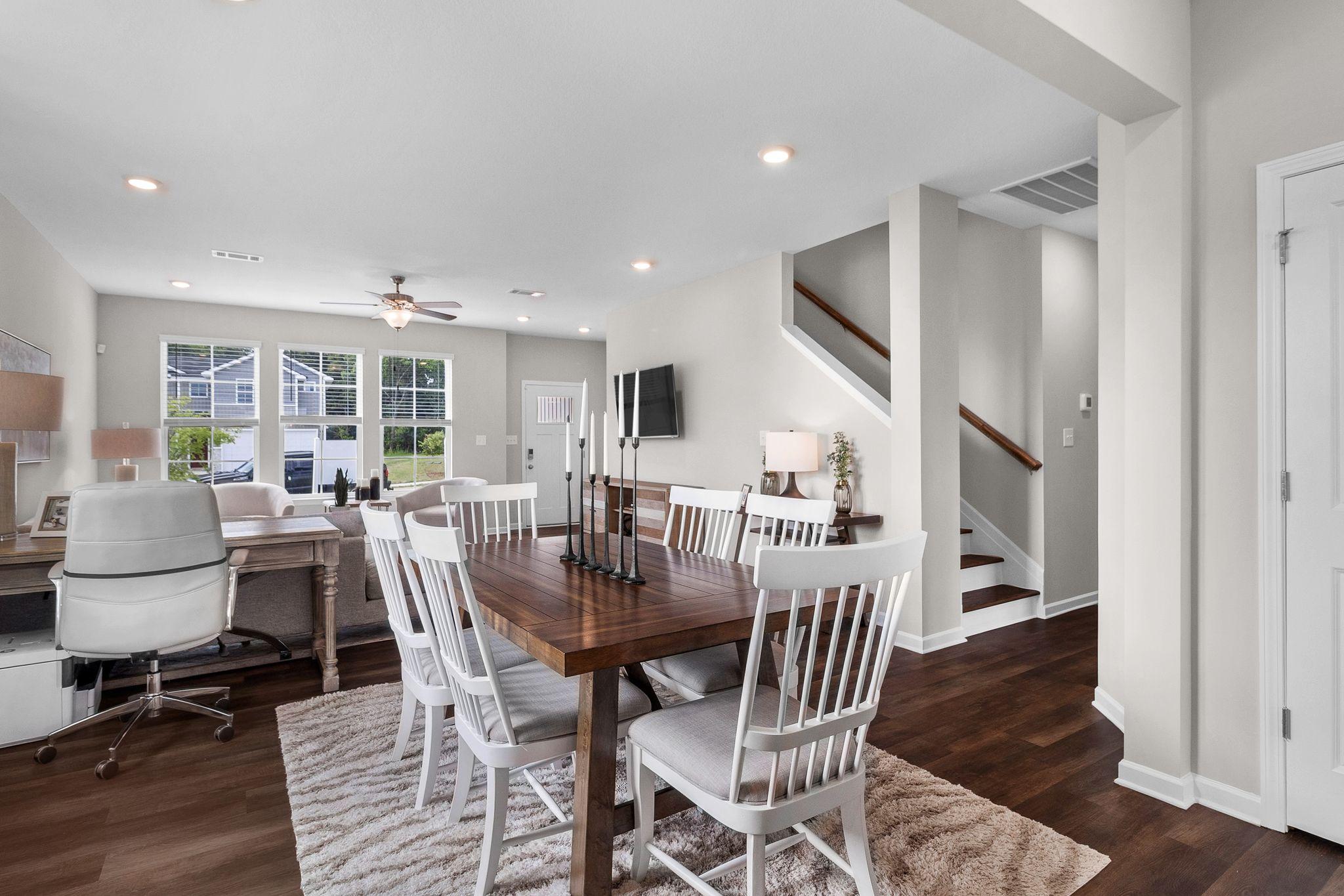 Spacious open-concept dining area at Ivy Glen in Perry Georgia by Evermore Homes with wooden table white chairs hardwood floors and living room view