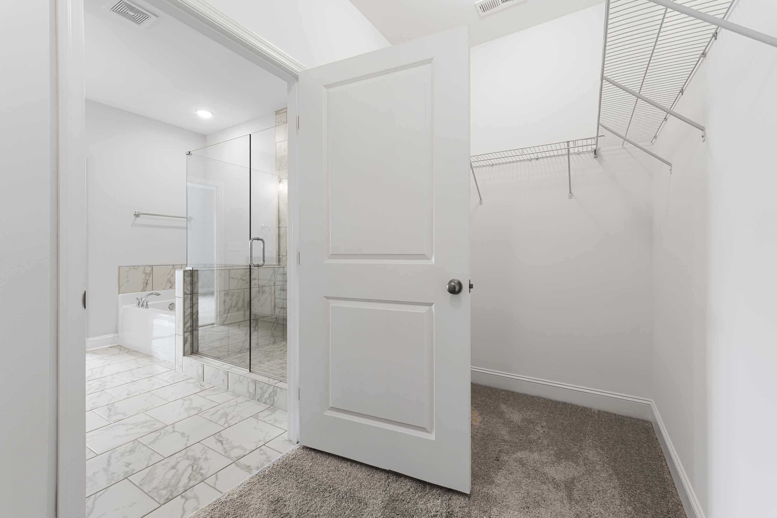 Modern master bathroom in The Copeland B featuring glass shower, freestanding tub, and adjacent walk-in closet