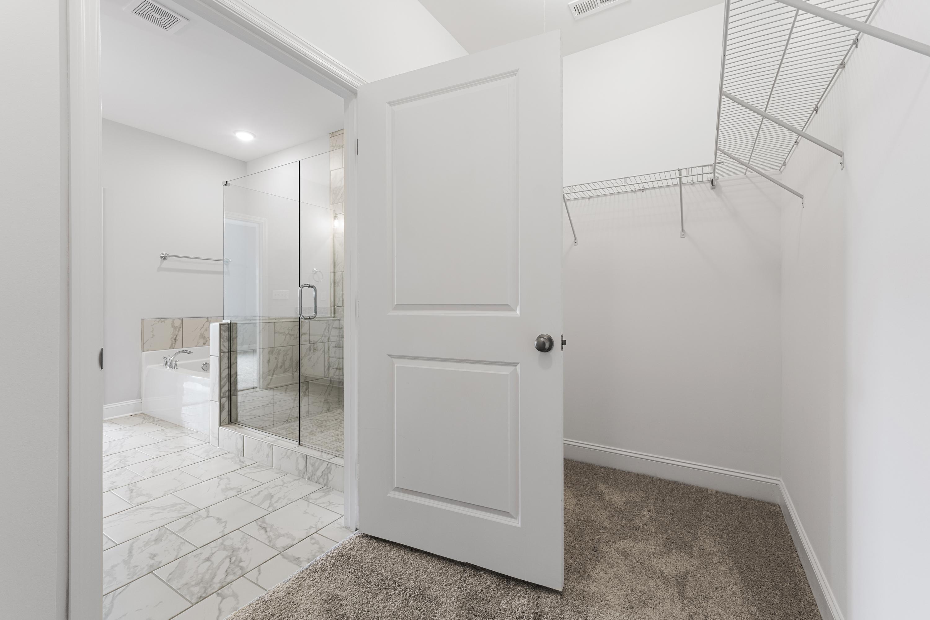 Master bathroom in The Copeland C featuring glass shower, soaking tub, double vanity, and adjacent walk-in closet