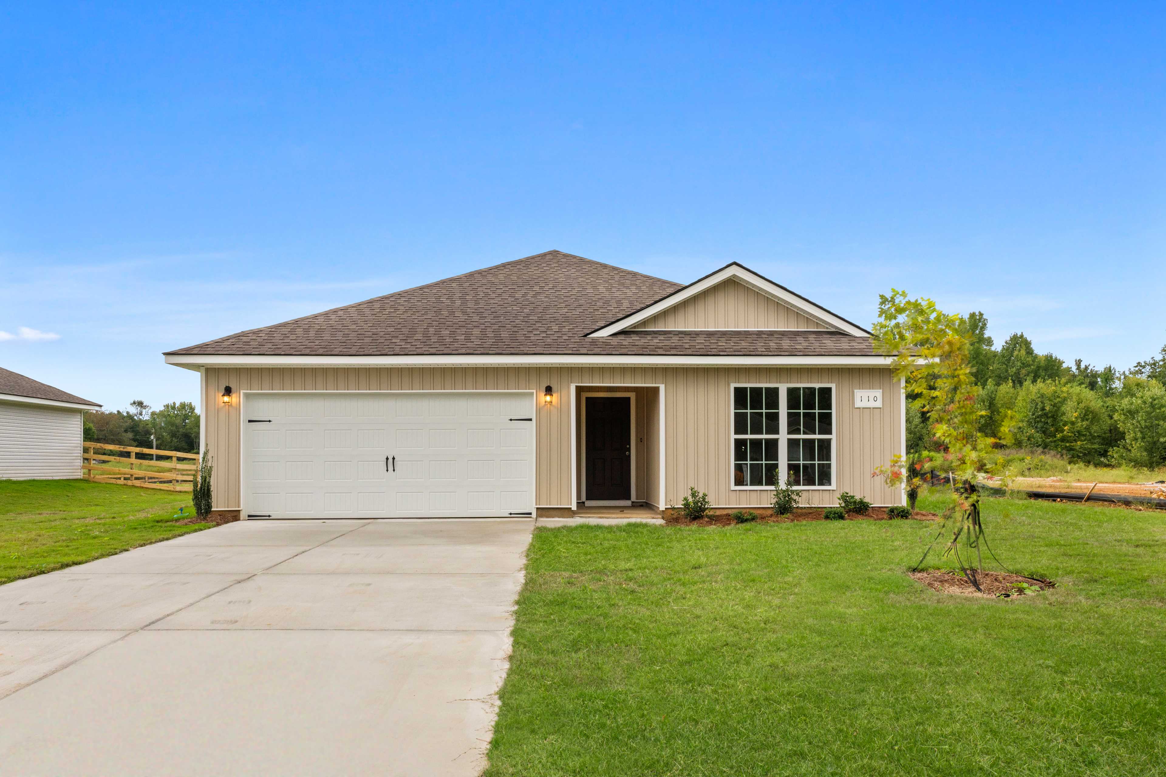 Beige ranch-style home exterior at Collins Lane in Meridianville, Alabama with attached garage and manicured lawn
