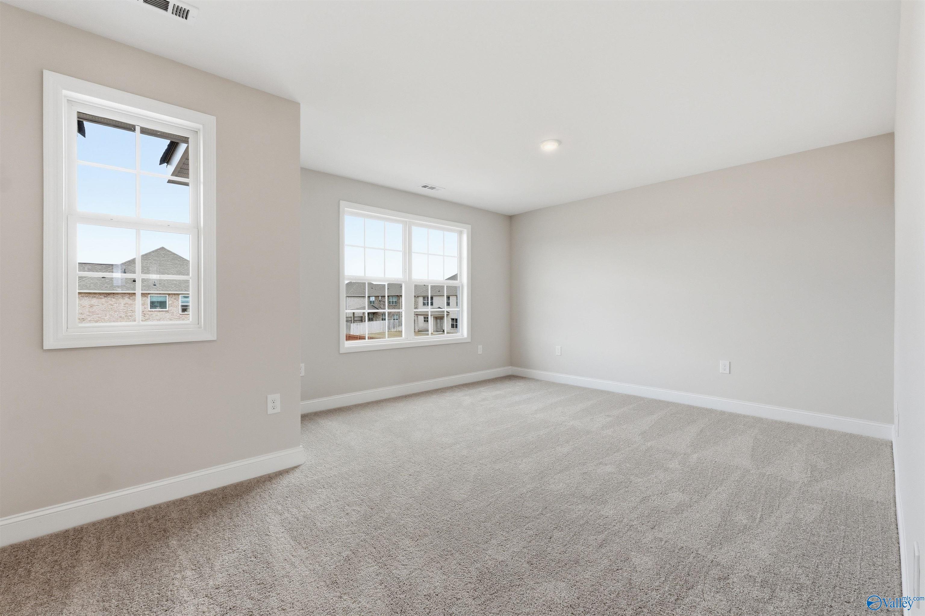 Spacious, carpeted bedroom with neutral walls in The Shelby D floor plan by Davidson Homes in Evergreen Mill, Alabama.