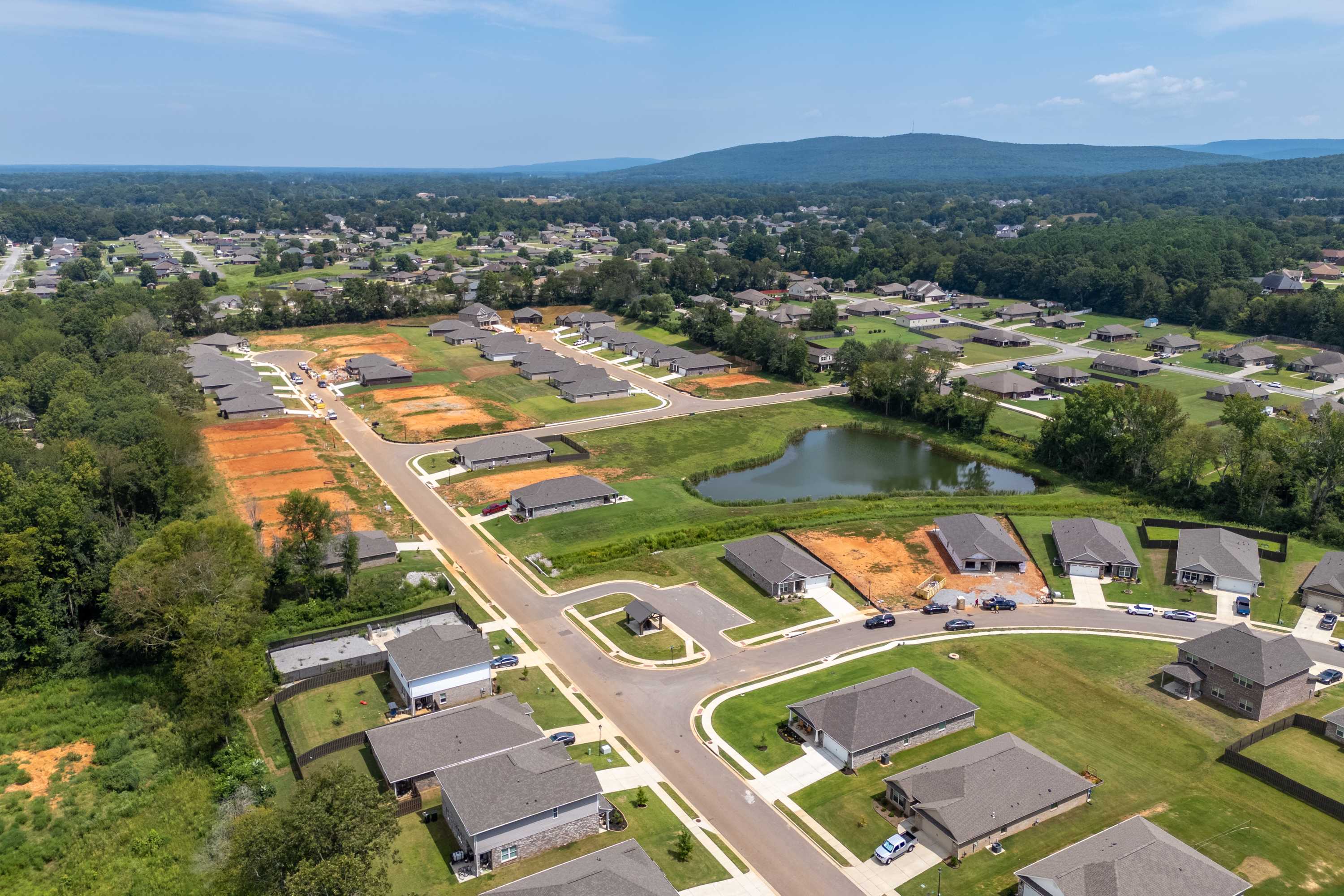Aerial view of Flint Meadows neighborhood in New Market Alabama featuring new Davidson Homes, pond, and wooded lots