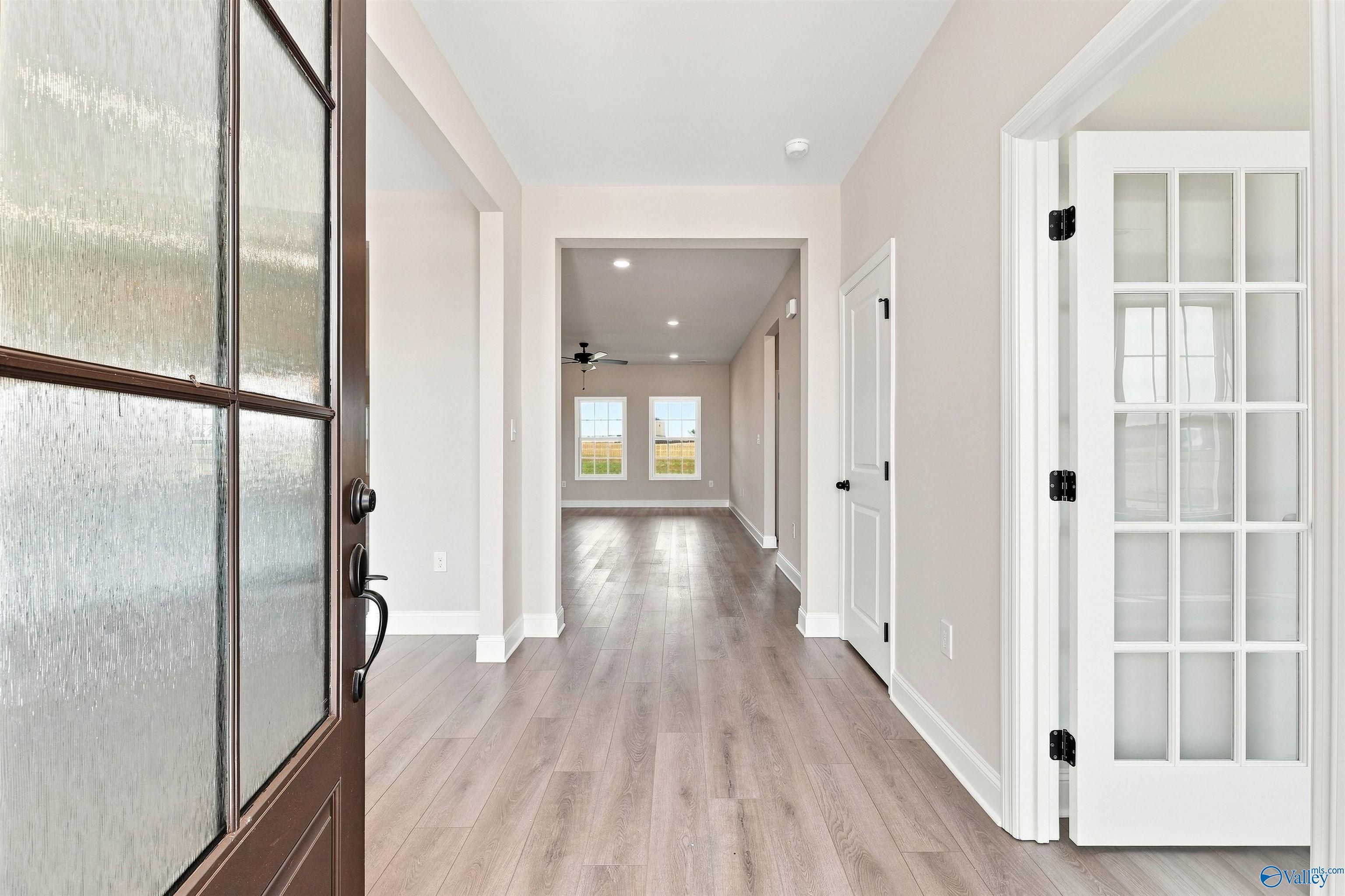 Bright foyer entryway with wood-look flooring and French doors in The Oxford floor plan at Kendall Farms, Toney, Alabama.