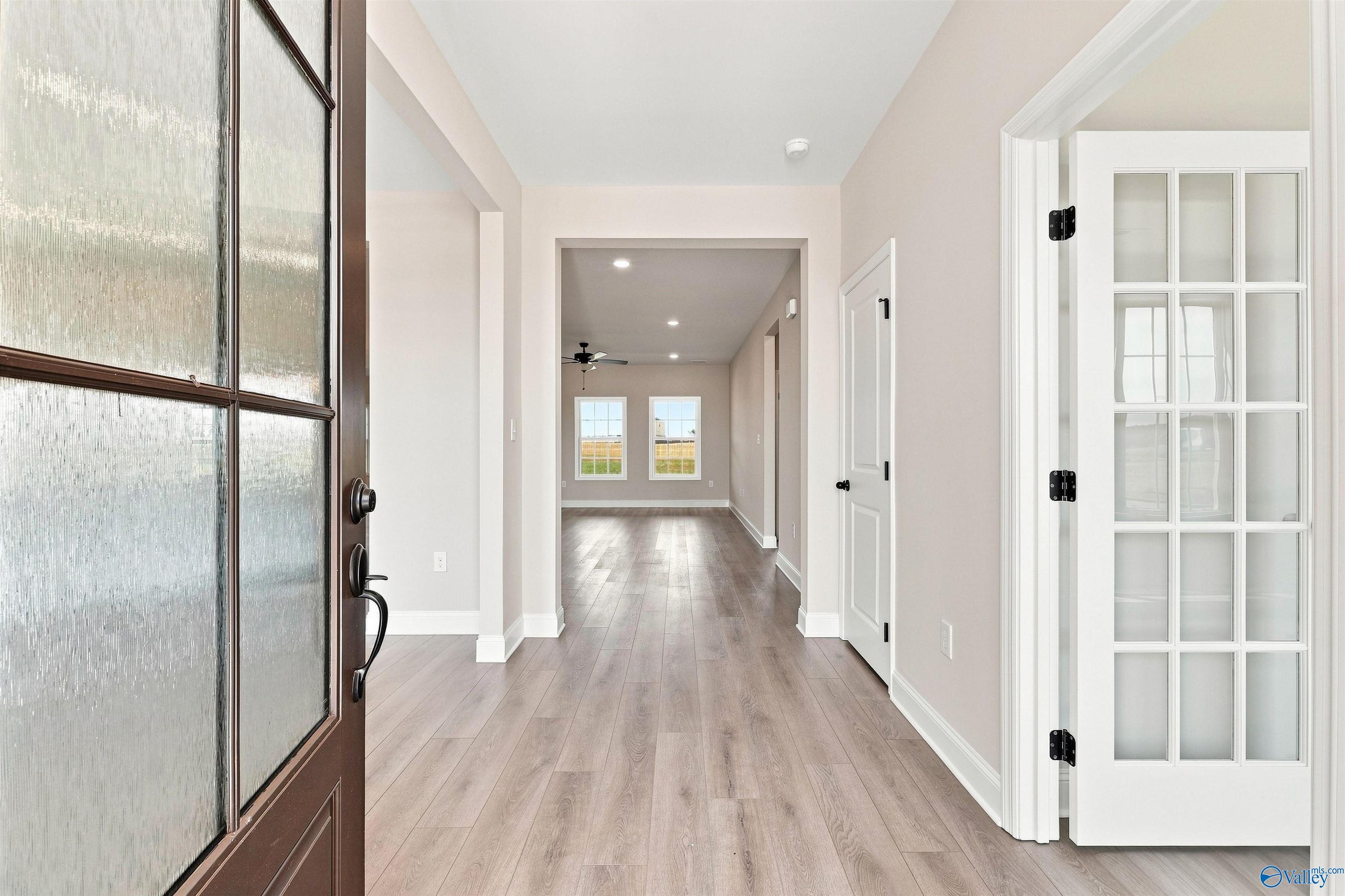 Bright foyer entryway with wood-look flooring and French doors in The Oxford floor plan at Kendall Farms, Toney, Alabama.