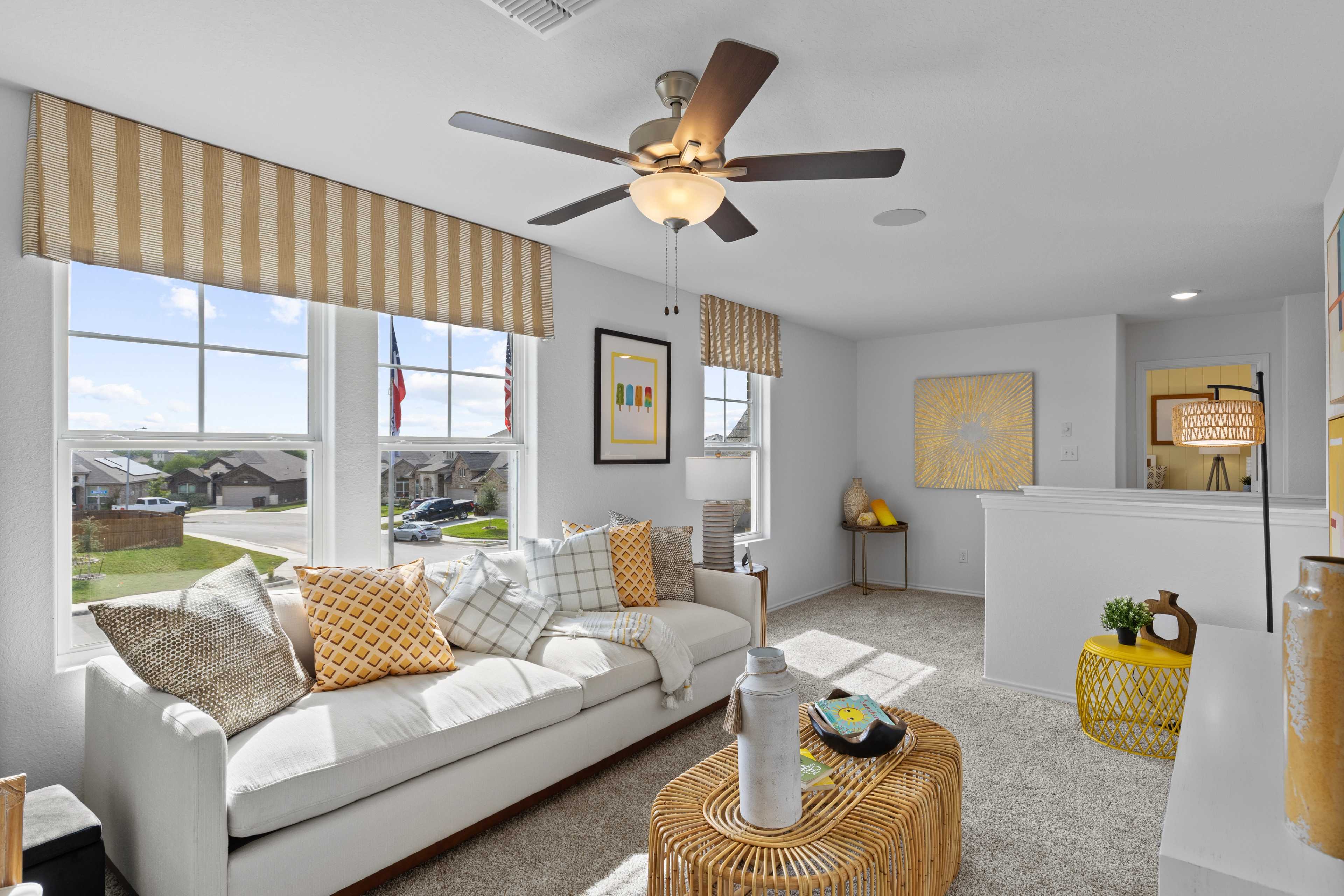Spacious living room at Horizon Pointe in Converse Texas by Davidson Homes with white sofa yellow accents ceiling fan and large windows