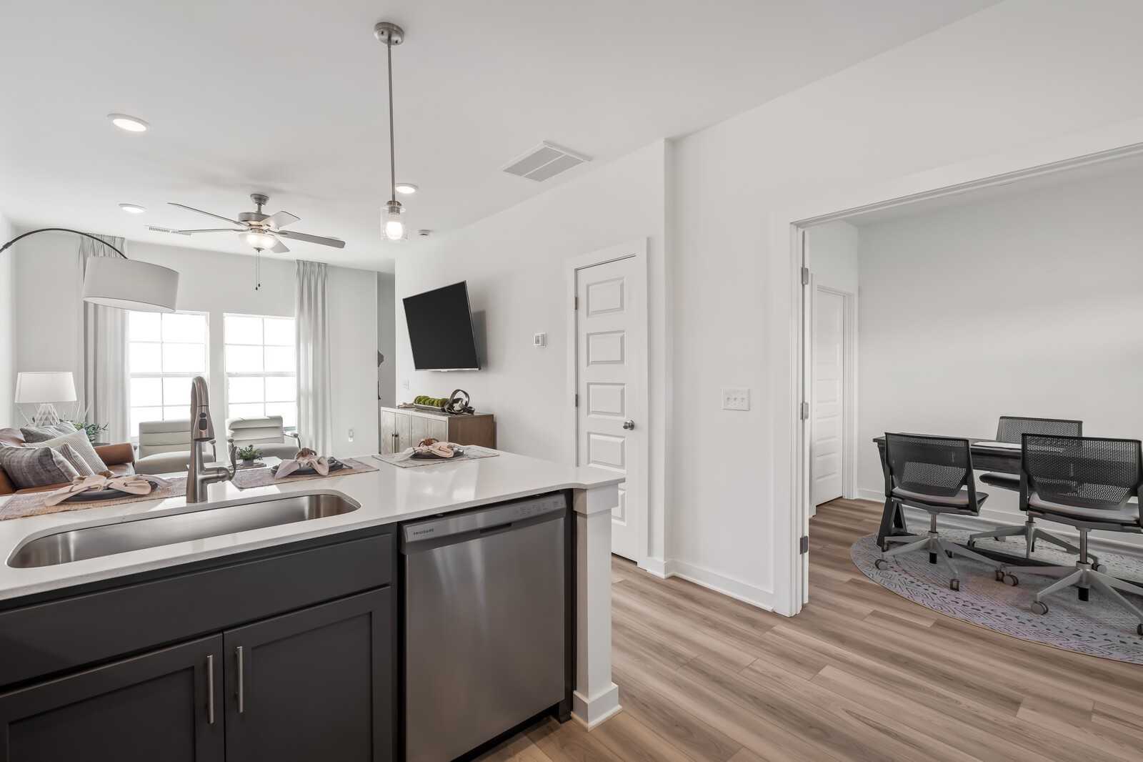Modern kitchen with dark island cabinets, stainless dishwasher, and open dining area in Davidson Homes Cumberland B, Gallatin TN
