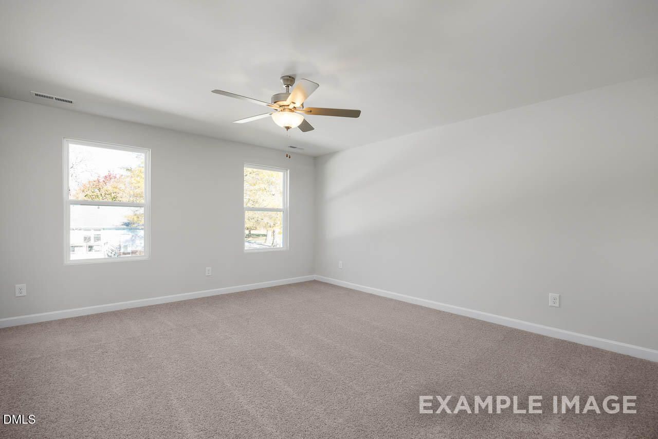 Bright bedroom with beige carpet, light gray walls, two large windows, and ceiling fan in Davidson Homes The Adalynn A, Lillington, NC