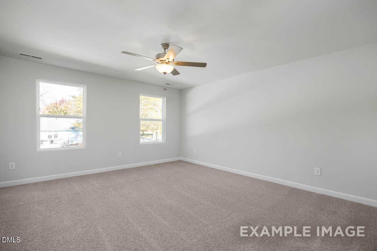 Bright bedroom with beige carpet, light gray walls, two large windows, and ceiling fan in Davidson Homes The Adalynn A, Lillington, NC
