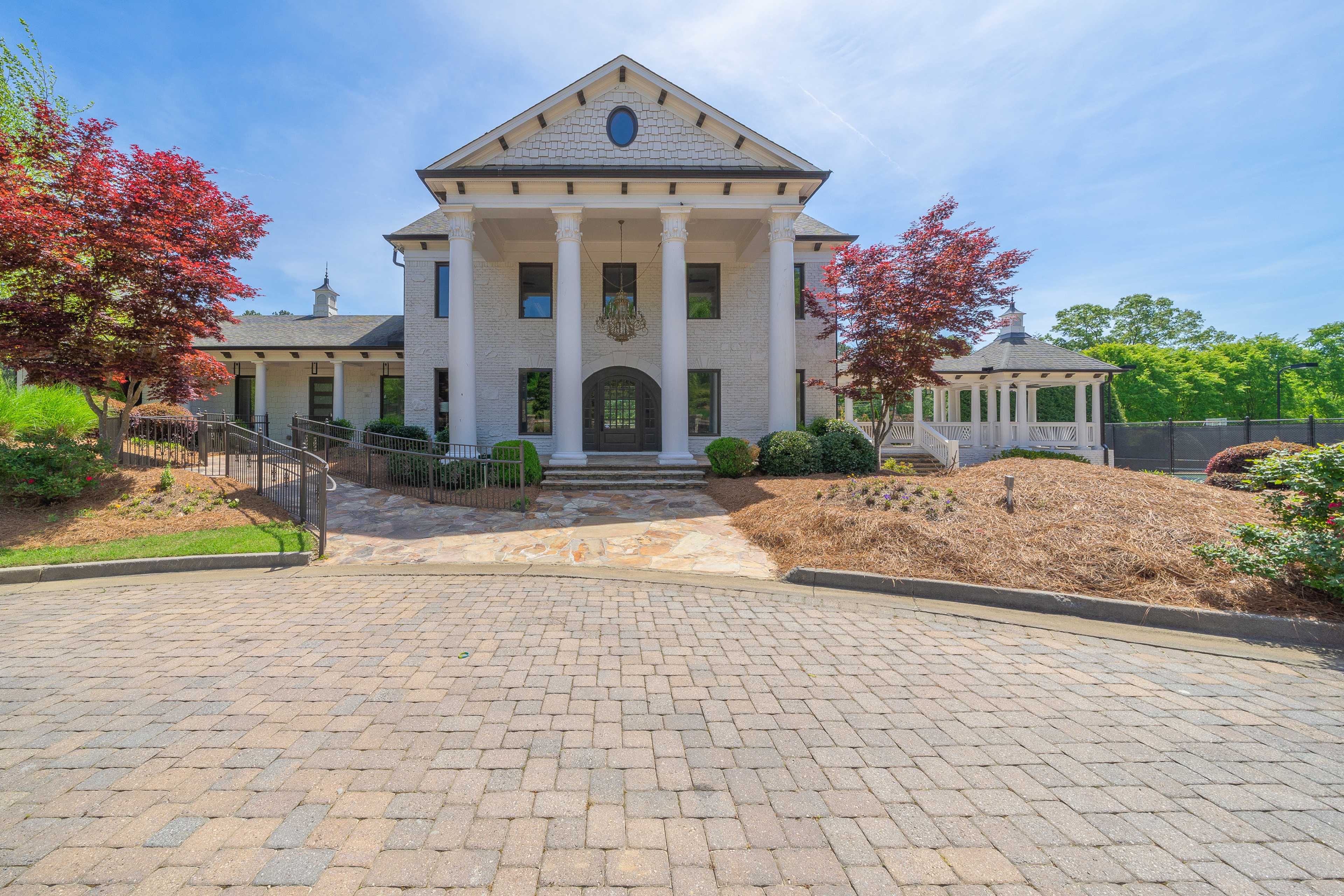 Grand columned home exterior at Mountainbrook in Cartersville GA with brick paver driveway, red maples and white gazebo