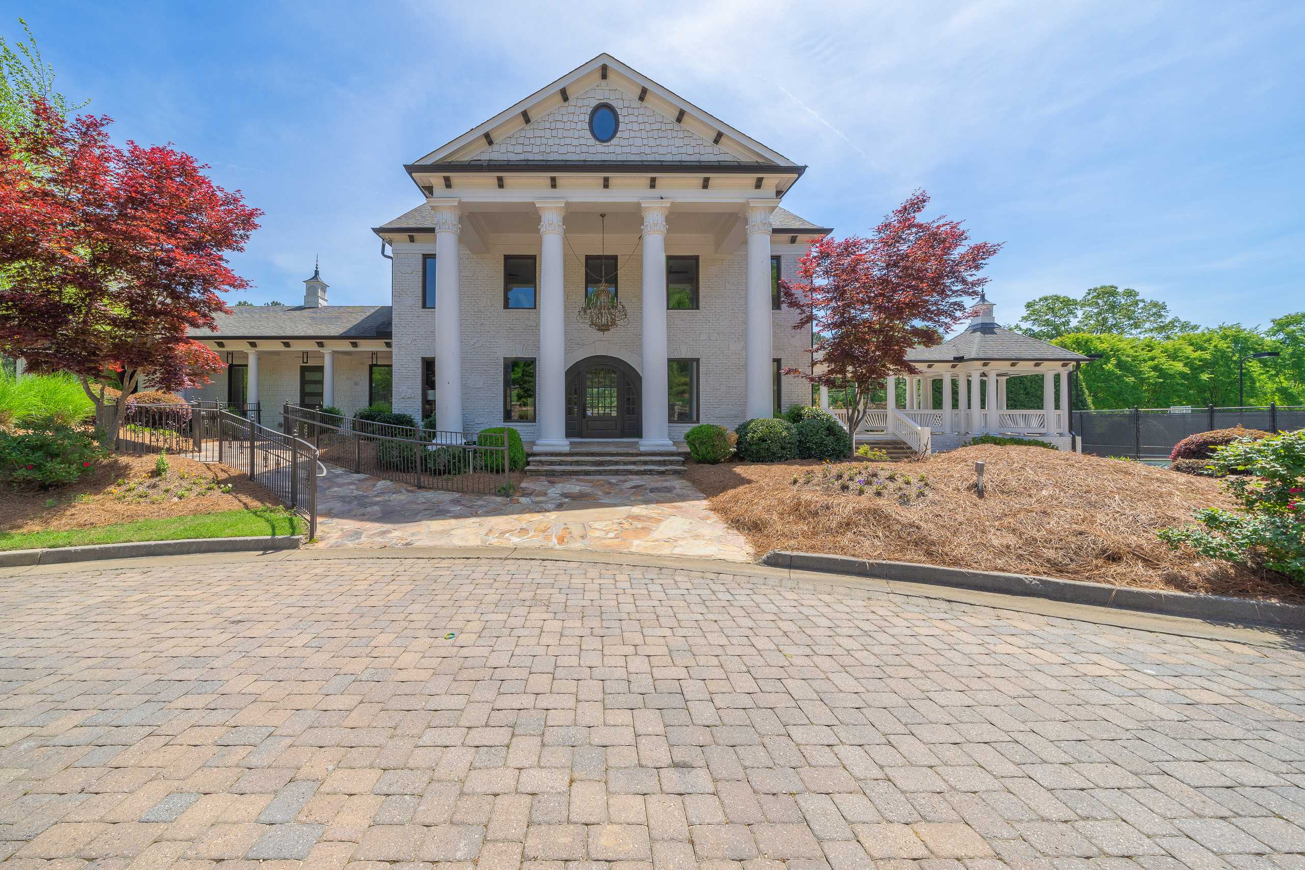 Grand columned home exterior at Mountainbrook in Cartersville GA with brick paver driveway, red maples and white gazebo