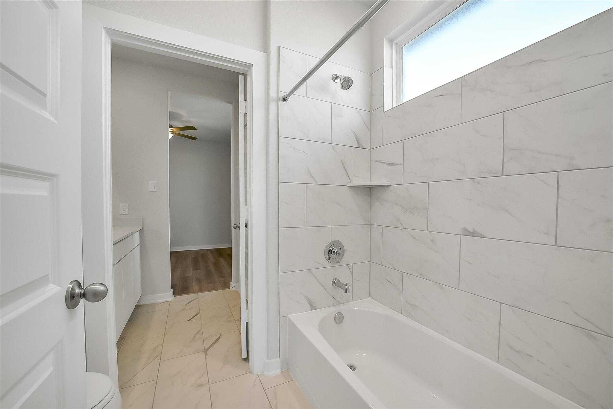 Modern bathroom with white subway tile shower, soaking tub, and vanity in Davidson Homes The Acadia A, Sunterra, Katy, Texas