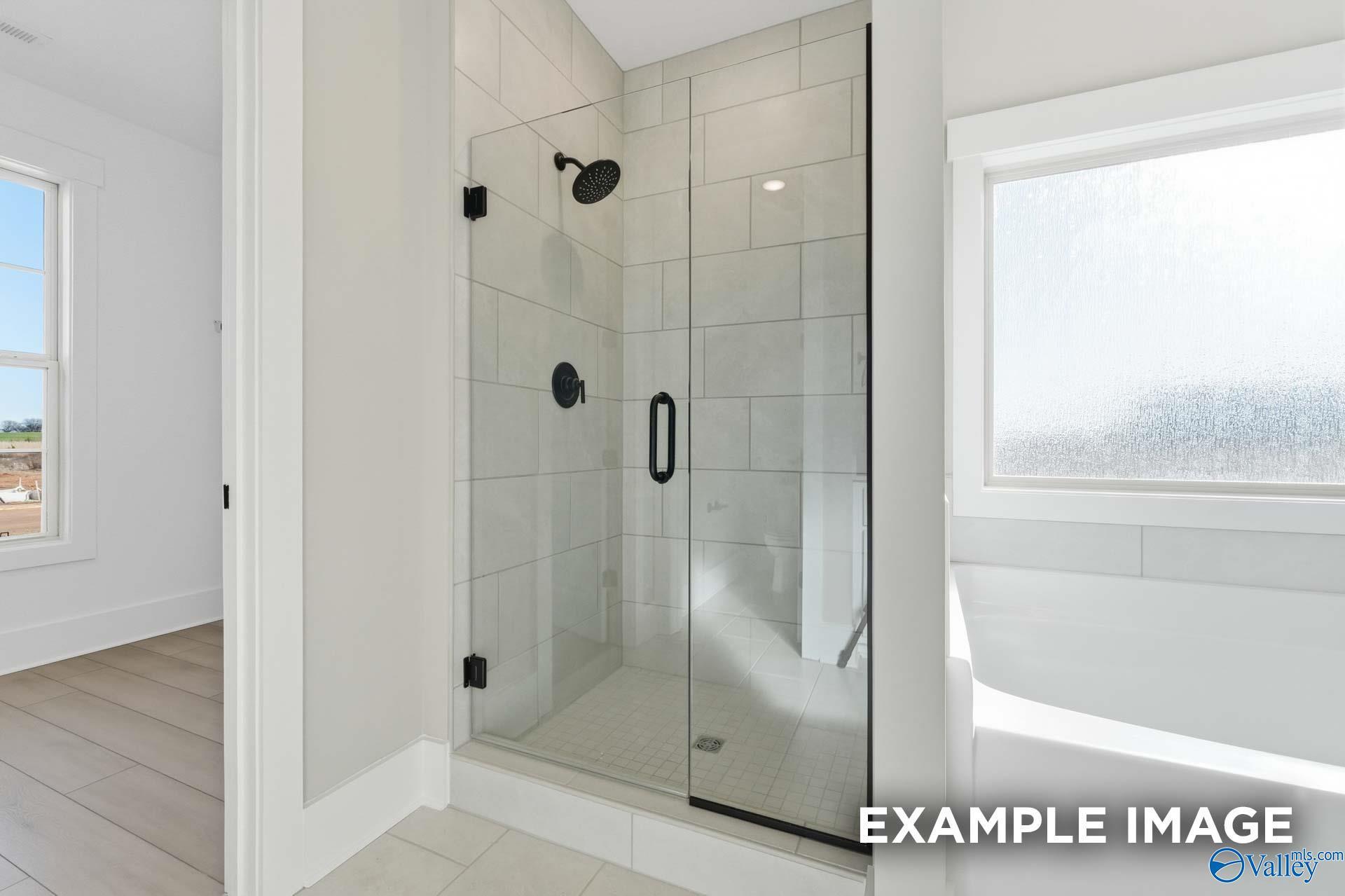 Modern frameless glass shower with rainfall head and subway tiles in The Emory master bath, Davidson Homes, Decatur AL